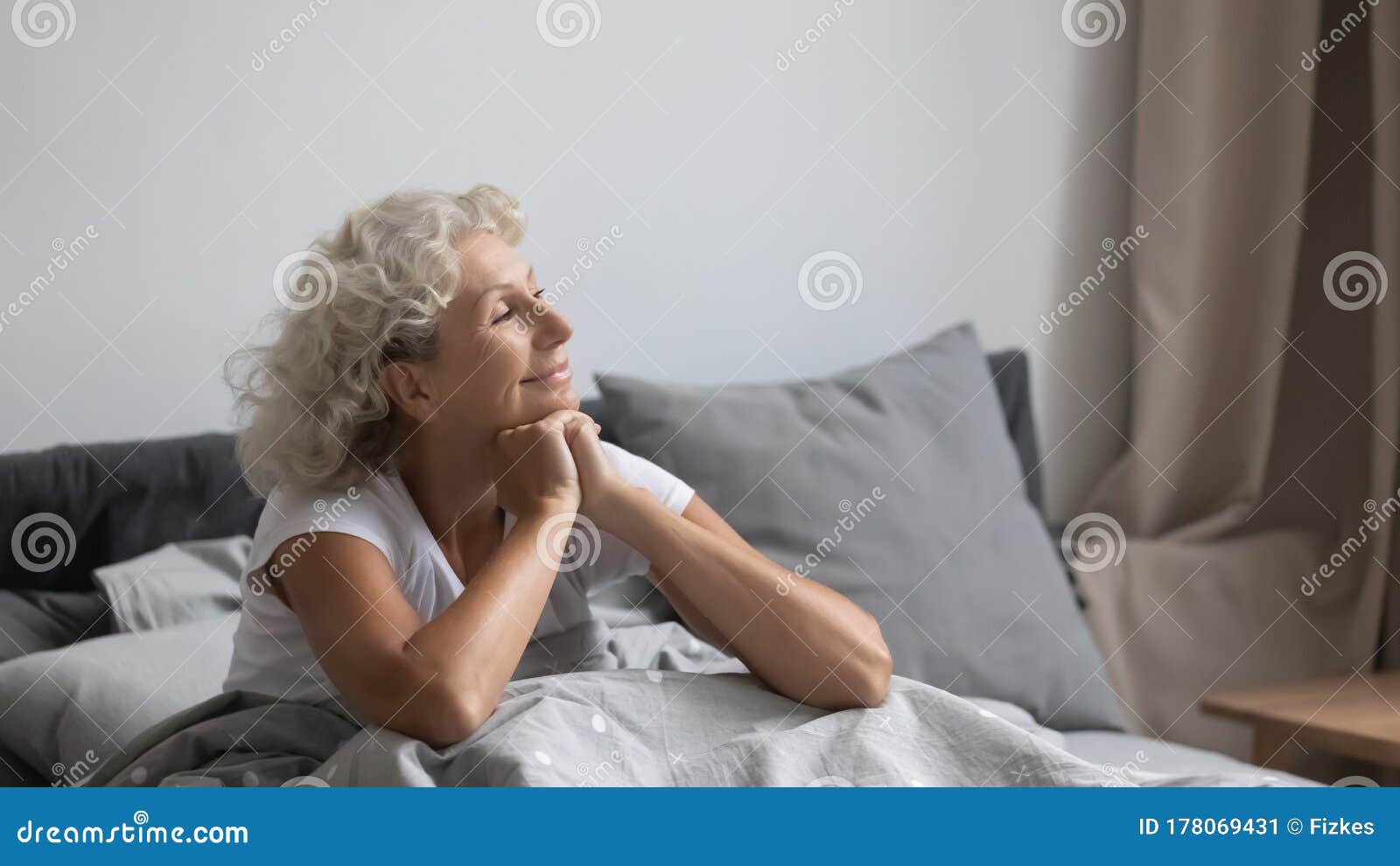 peaceful middle aged woman welcoming new day in bedroom.