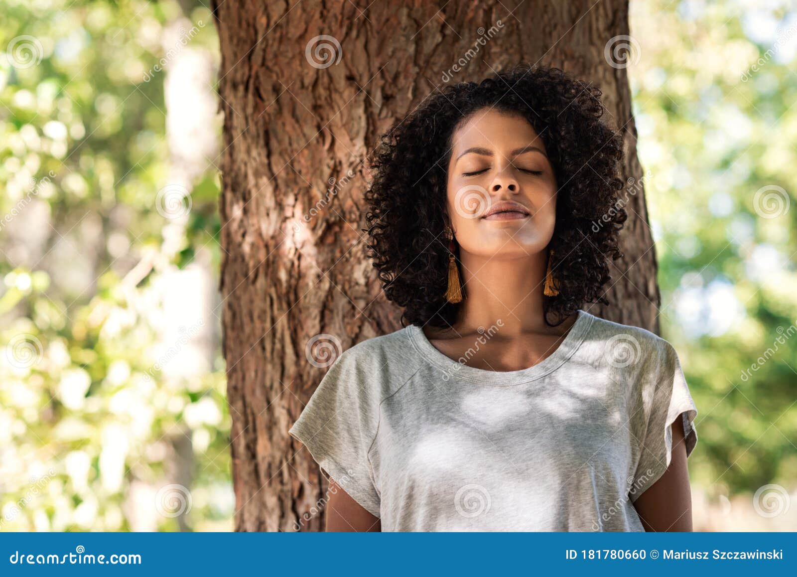 peaceful woman leaning against a tree with her eyes closed