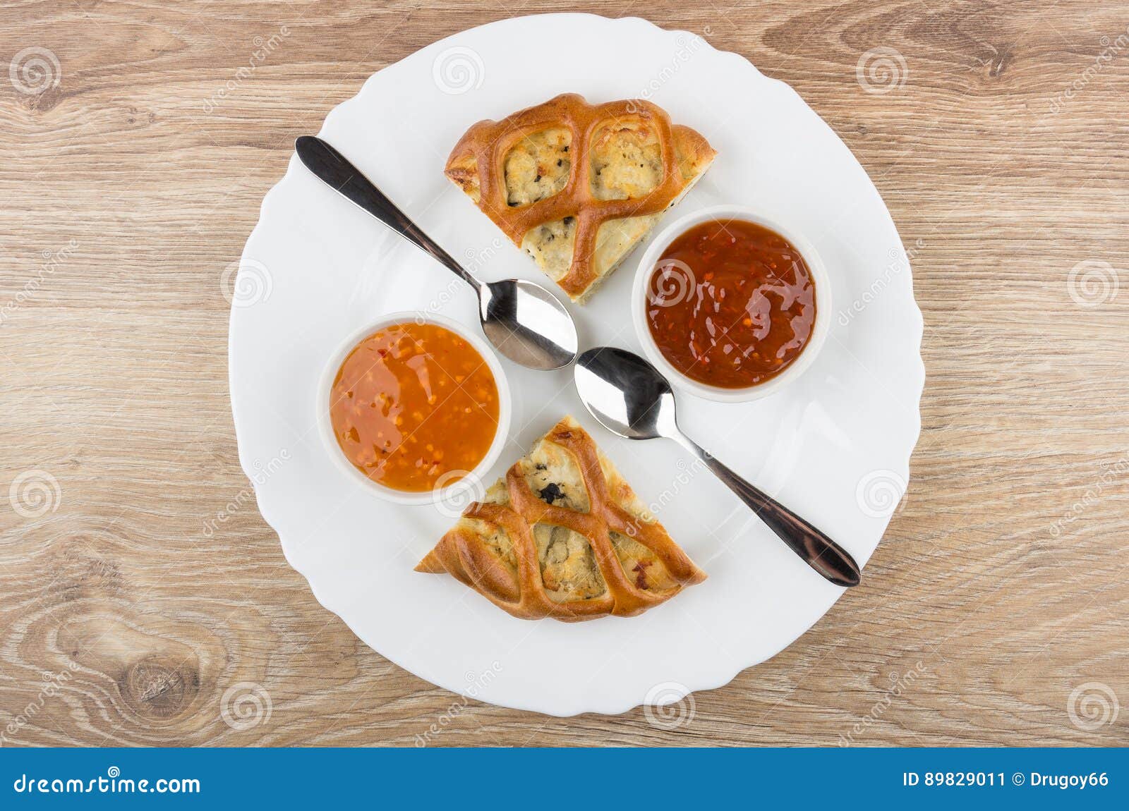 Pedazos de empanada rellenos, de salsas en cuencos y de cucharas en plato en la tabla de madera Visión superior