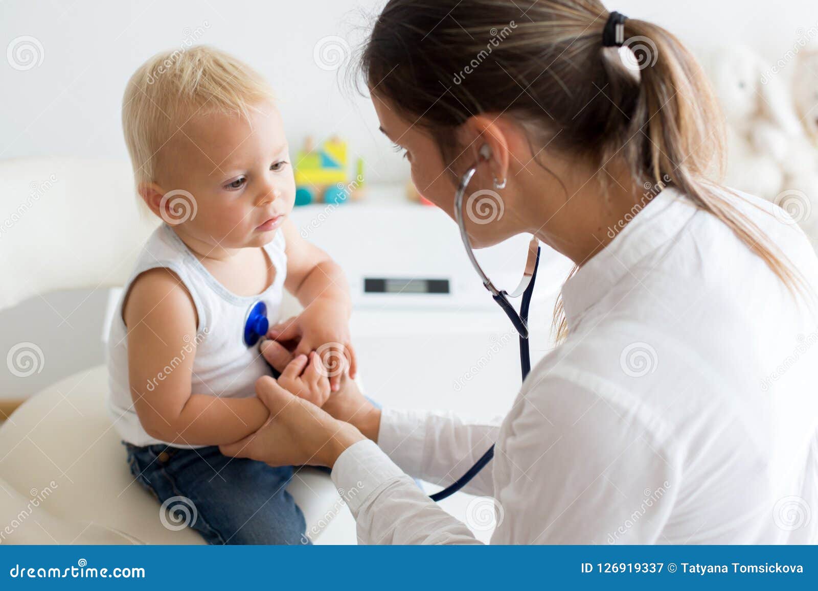 pediatrician examining baby boy. doctor using stethoscope to listen to kid