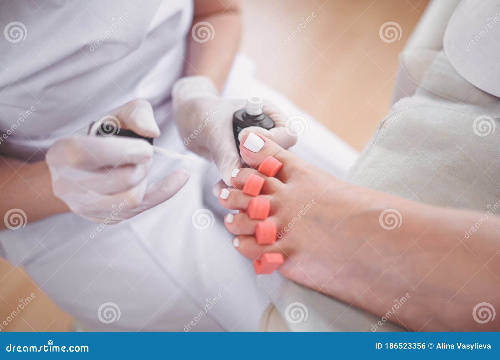 Pedicurist Doing White Nail Polish on Client Legs Using Toe Finger