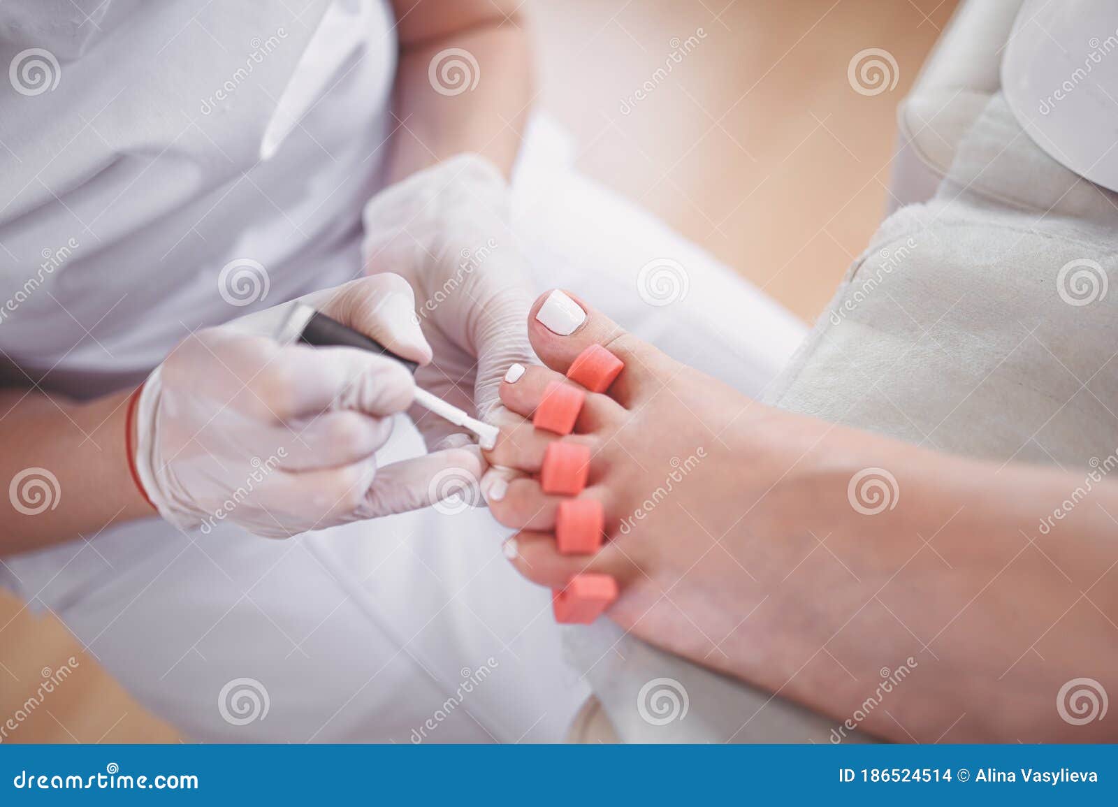 Pedicurist Doing White Nail Polish on Client Legs Using Toe Finger