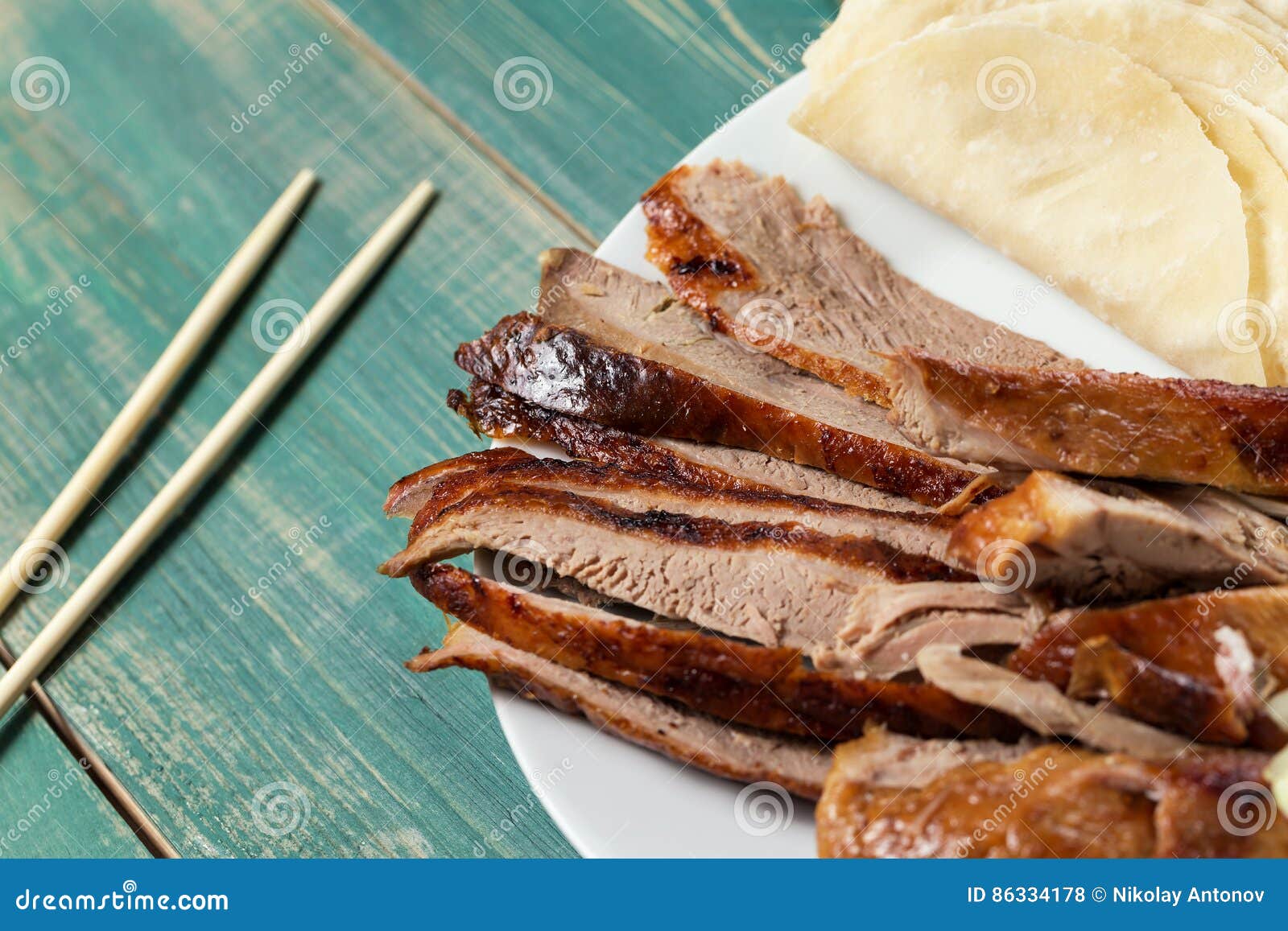 peking duck - chinese roast duck pancakes on wooden green table with chopsticks close up