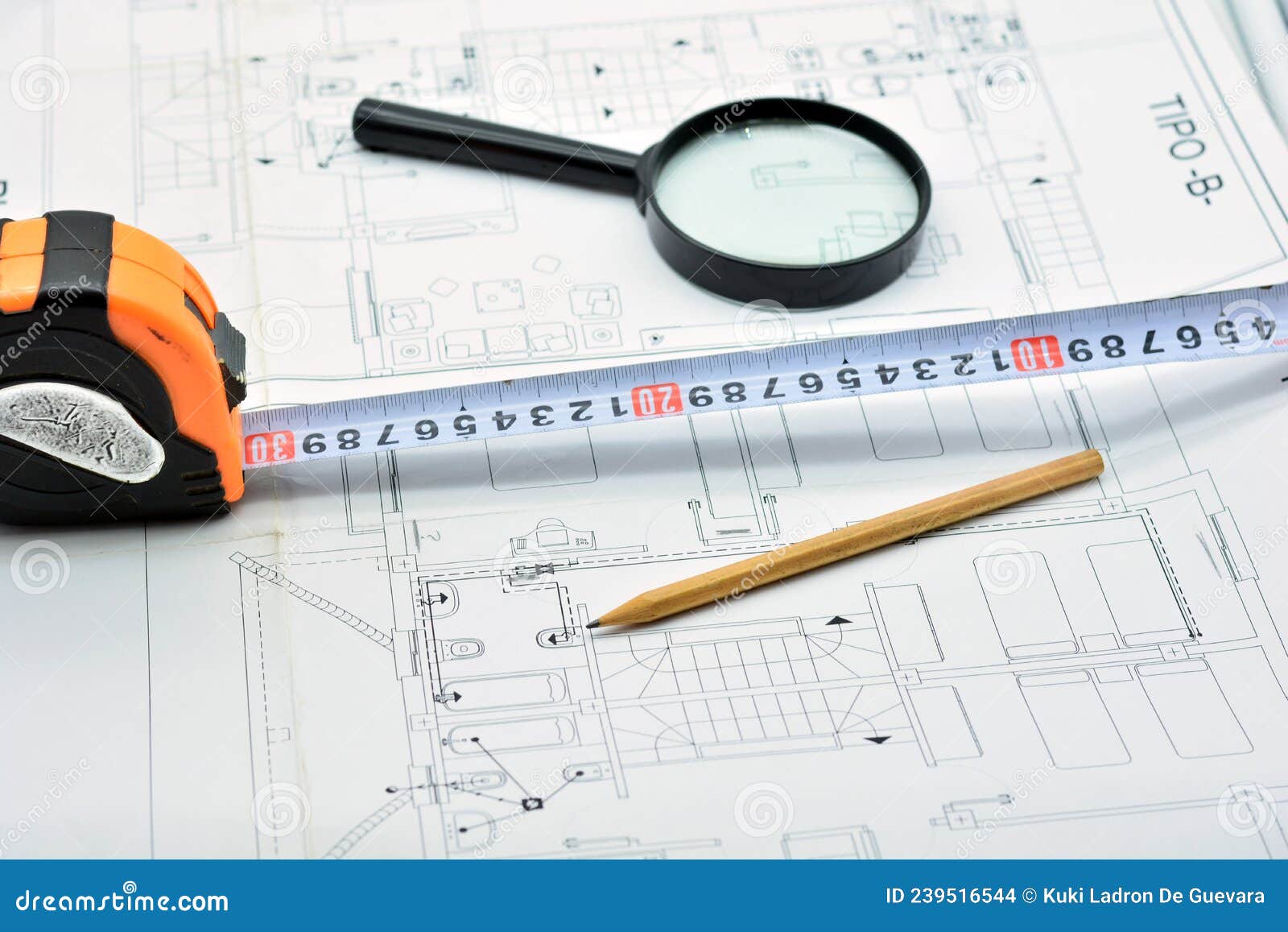 pencil, ruler and magnifying glass on top of a plan