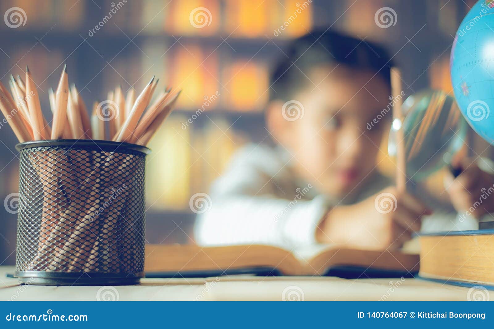 pencils on a wooden table and asian child industrious is sitting at a desk . background. educational background