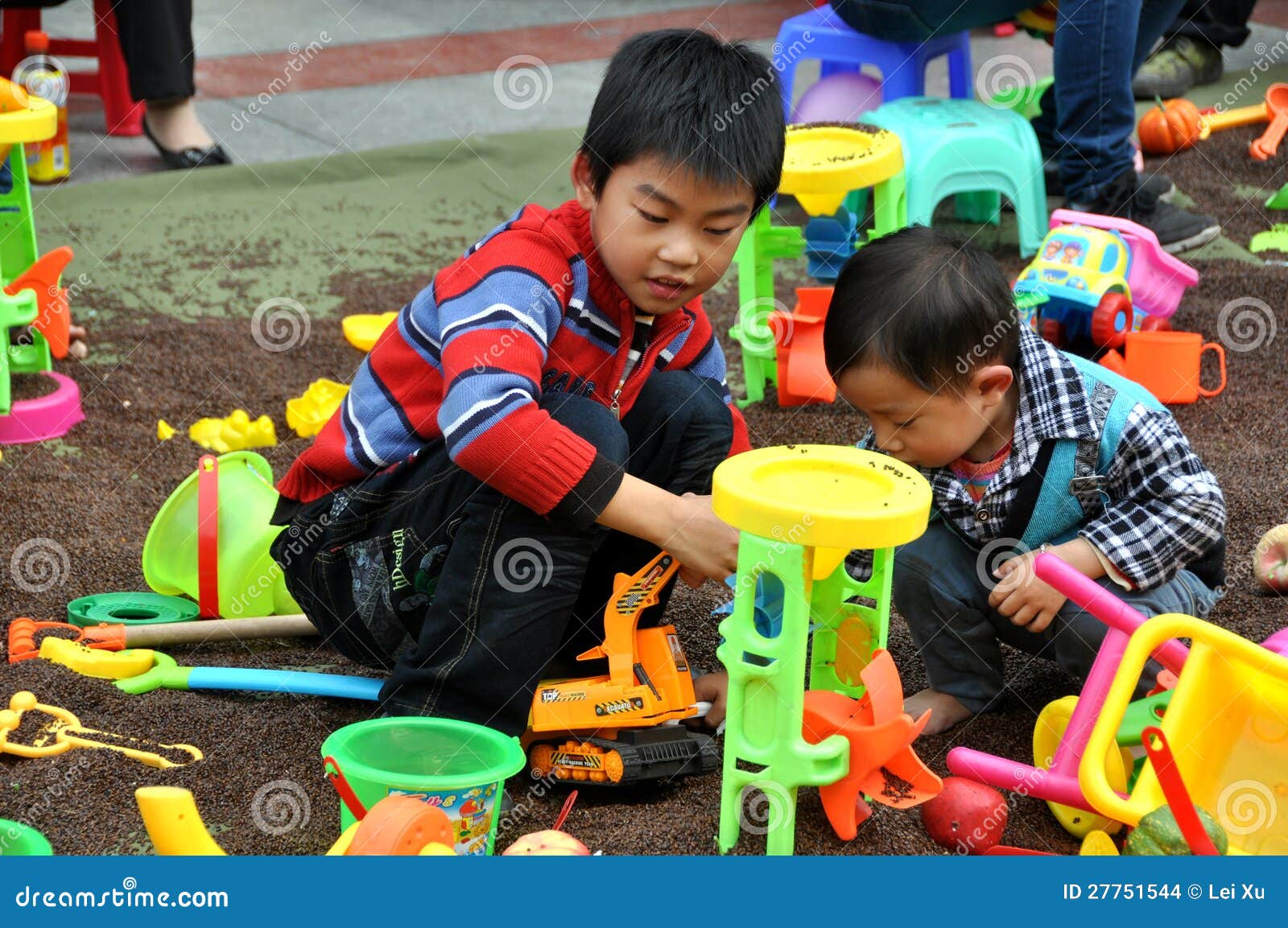 Pengzhou，中国： 作用的子项与玩具. 使用与五颜六色的塑料玩具的二个小男孩在一个大室外玩耍区域在Pengzhou的新的正方形，四川省，中国。