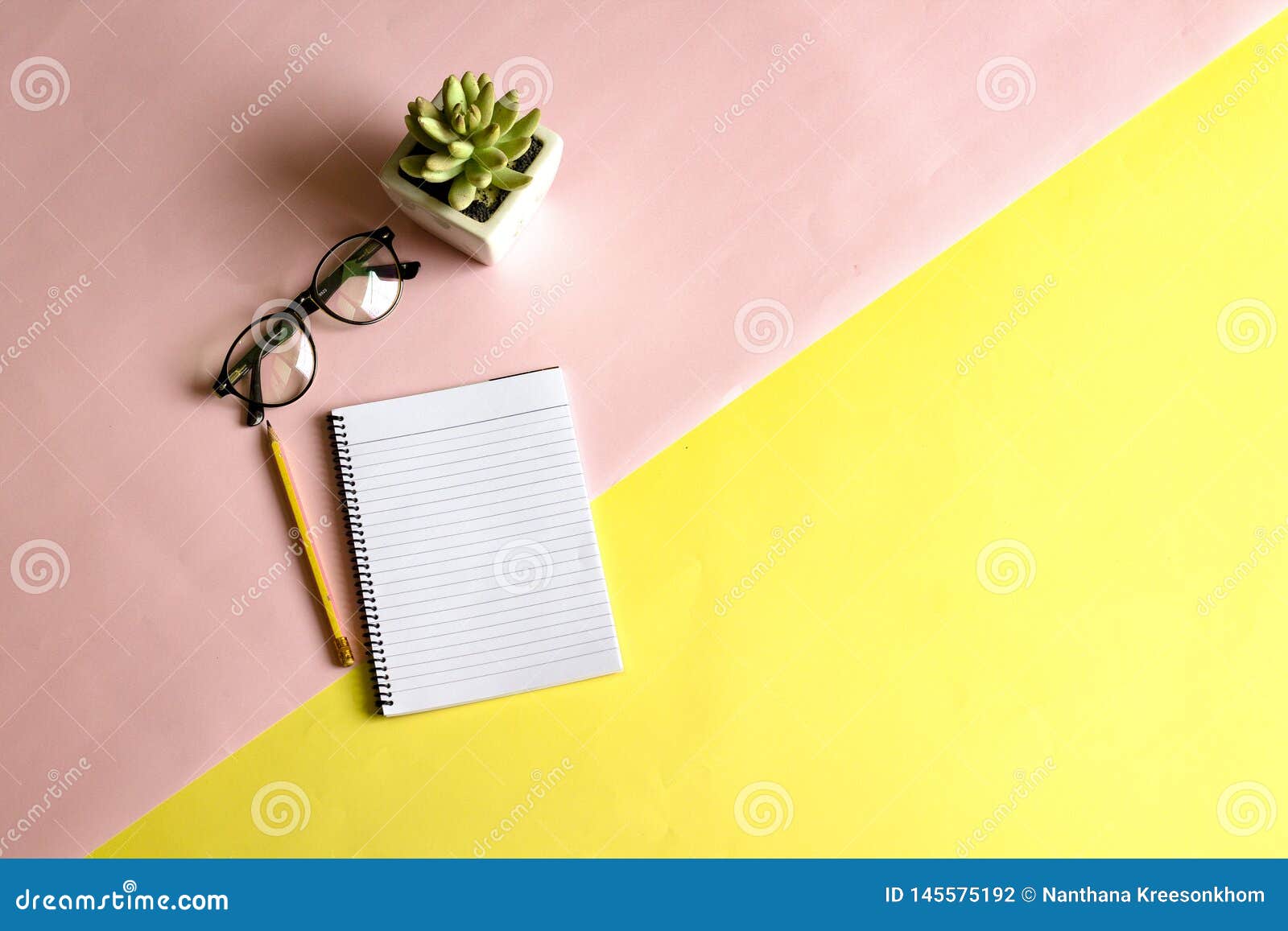 Pennen, notitieboekjes en glazen op het bureau worden geplaatst dat. Vrouwen op het het werkgebied met dahlia's en glazen die van lichtgeel en roze, de lijst leggen achter de achtermening van vrouwen