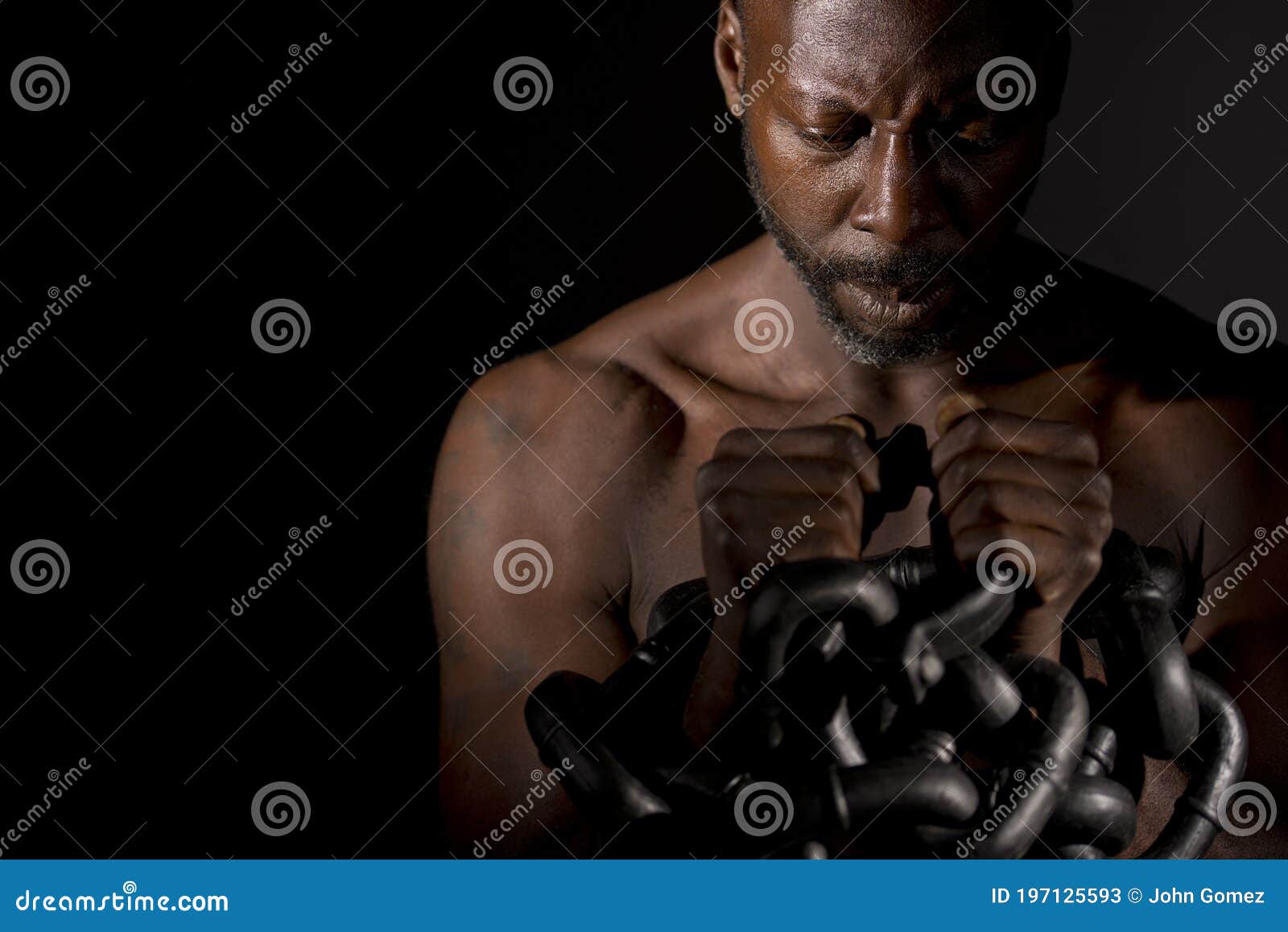 pensive black man holding large heavy chains.