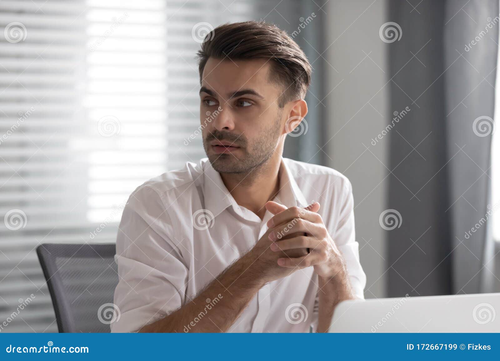 pensive male employee look to side listen to coworker talk