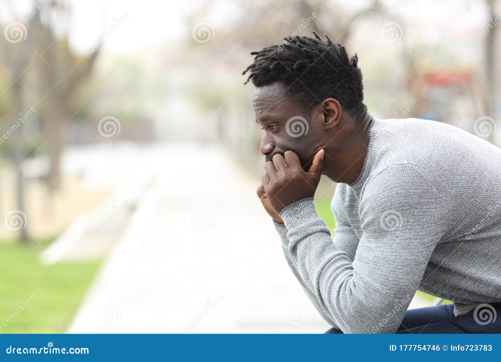 pensive serious black man looking away on a park