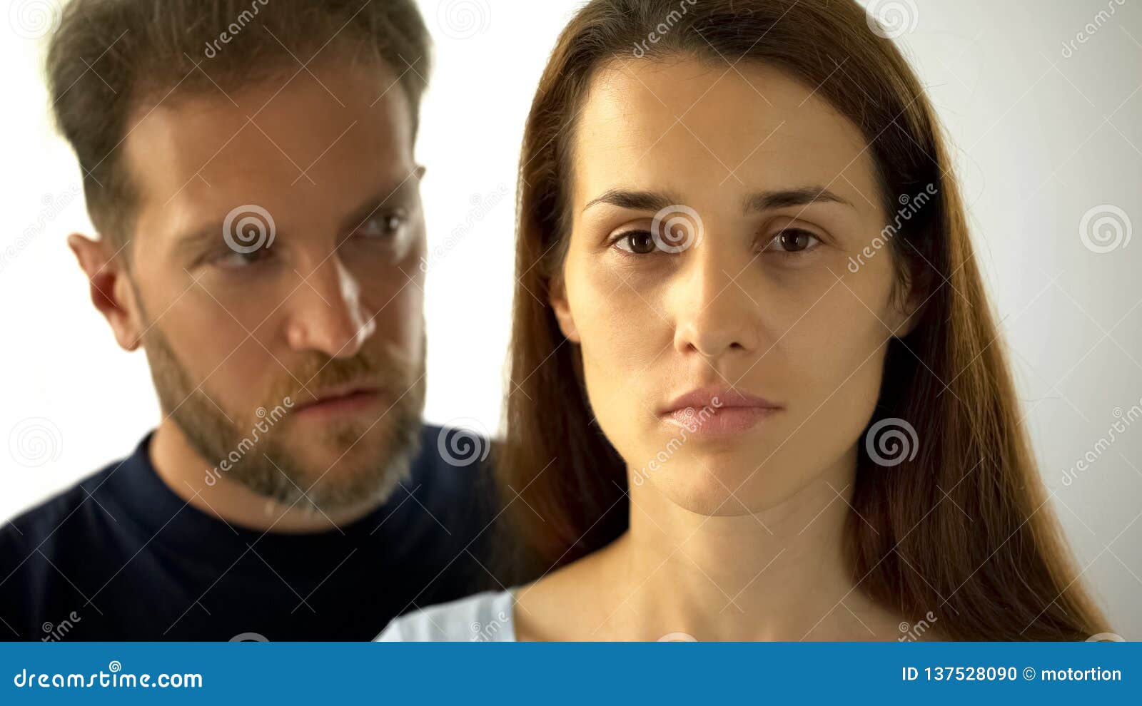 pensive woman looking at camera man behind wife, inability to make own decisions