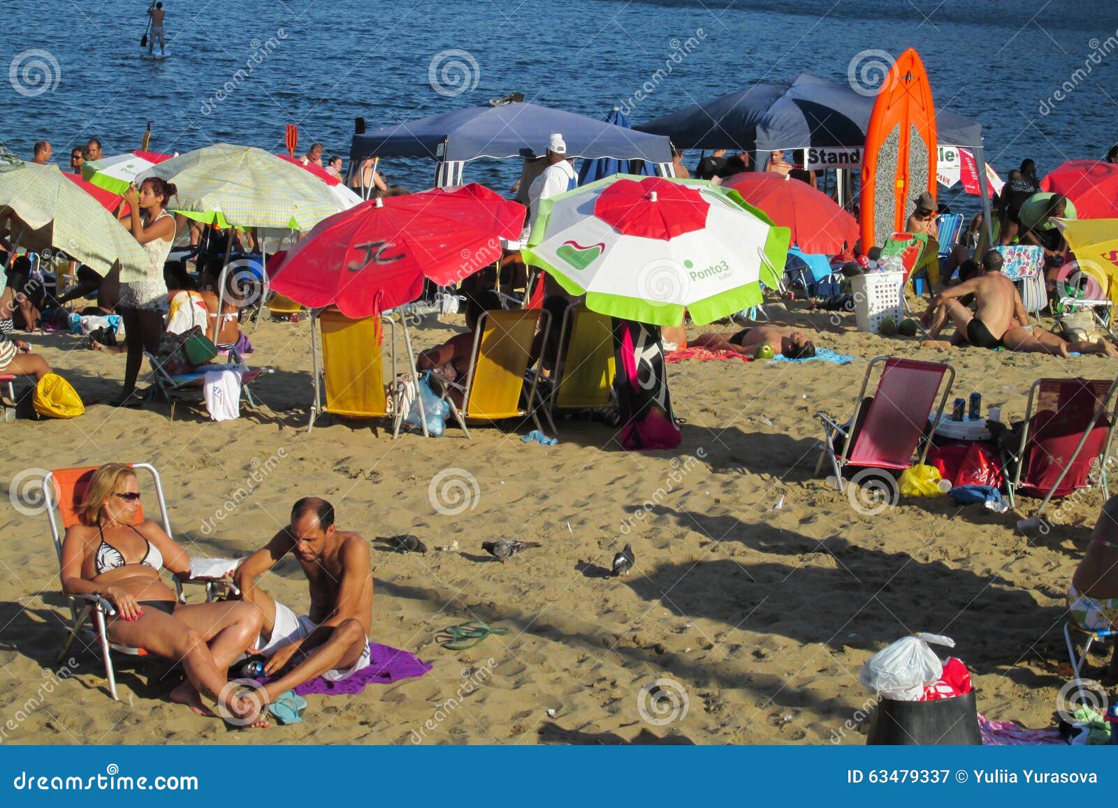 People at Copacabana beach, Rio de Janeiro. People swiming in huge the ocean waves at Rio de Janeiro beach, Brazil. Big dangerous ocean and seawaves, good for surfing. People having fun and sunbathing on nice sand beach in Rio, Copacabana and Ipanema beaches