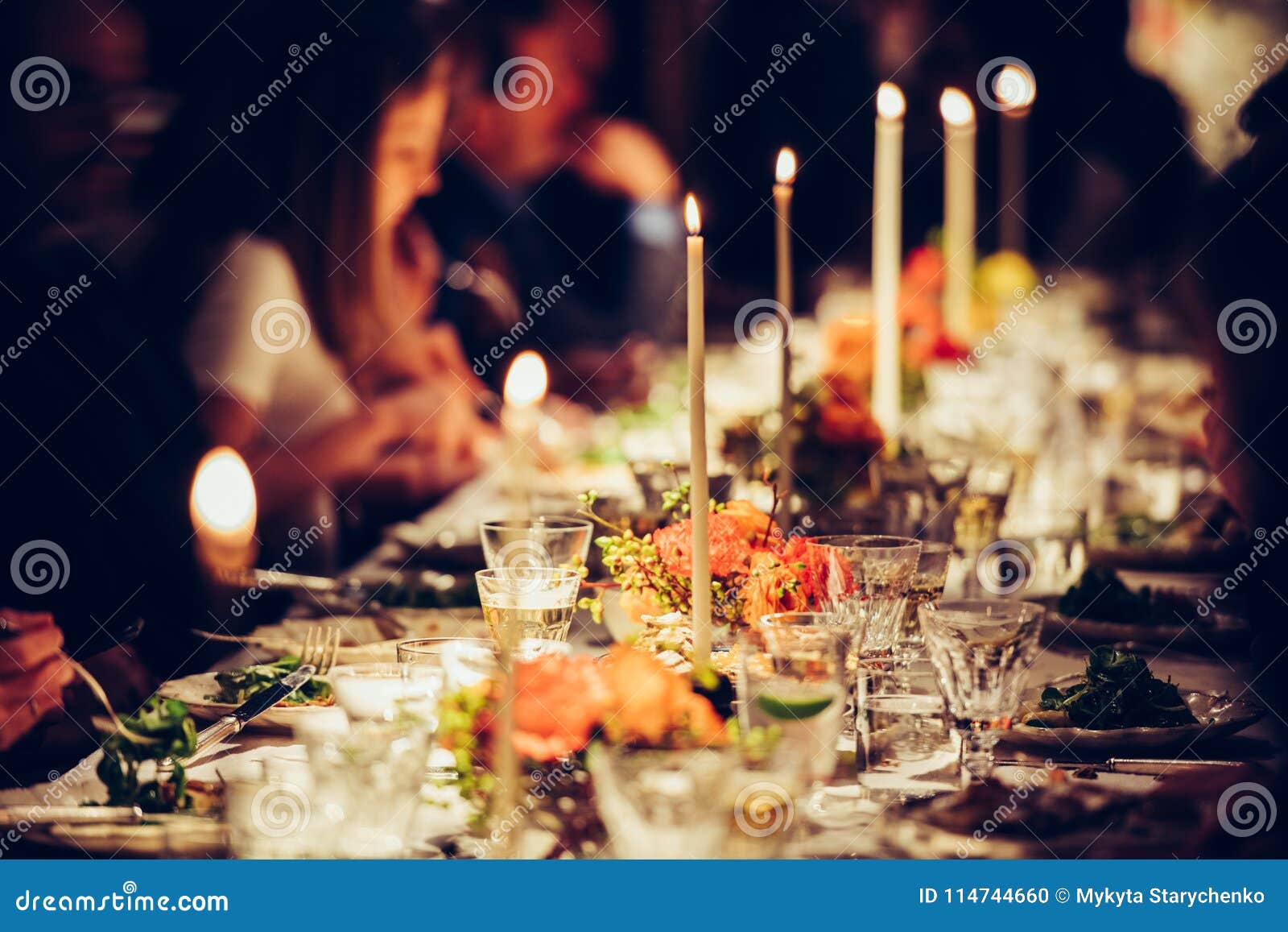 people enjoy a family dinner with candles. big table served with food and beverages