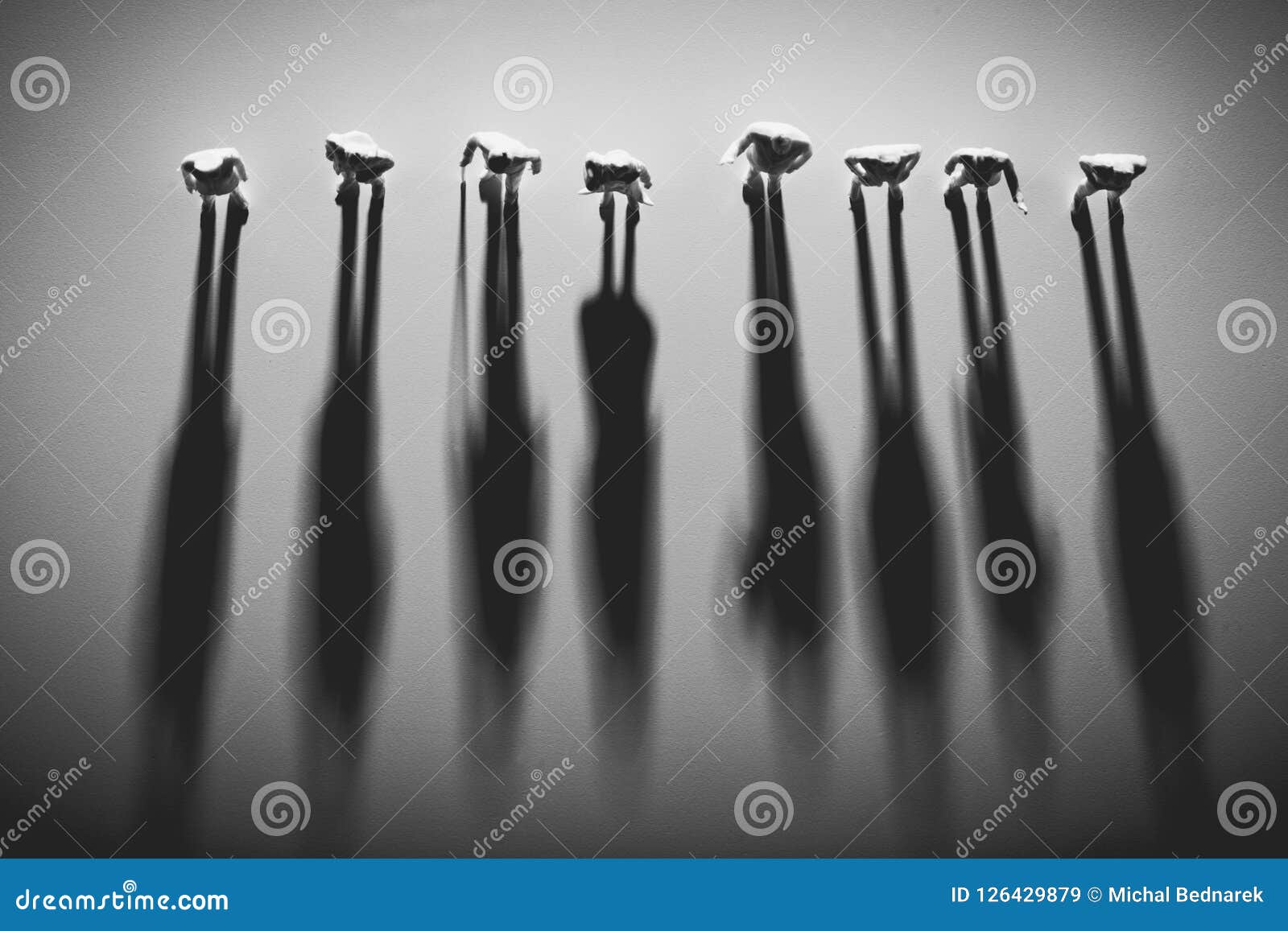 people figures standing in a row, casting shadows.