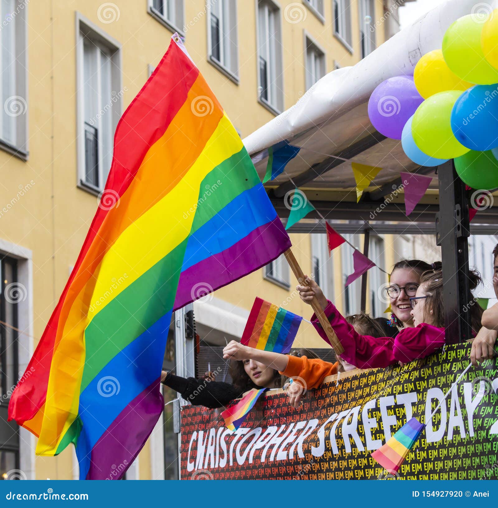 People on a Float Waving a Big Rainbow Flag Attending the Gay Pride