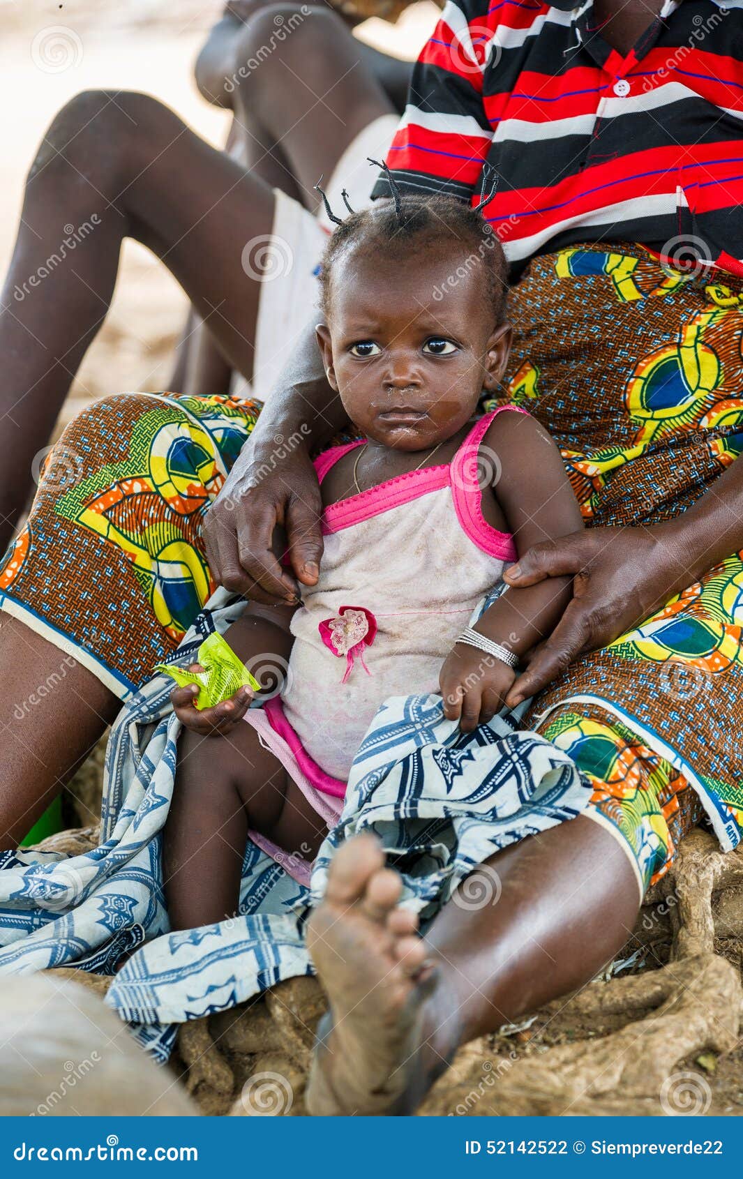 People in GHANA. ACCRA, GHANA - MARCH 6, 2012: Unidentified Ghanaian woman and her little baby sit near the tree in the street in Ghana. People of Ghana suffer of poverty due to the unstable economic situation
