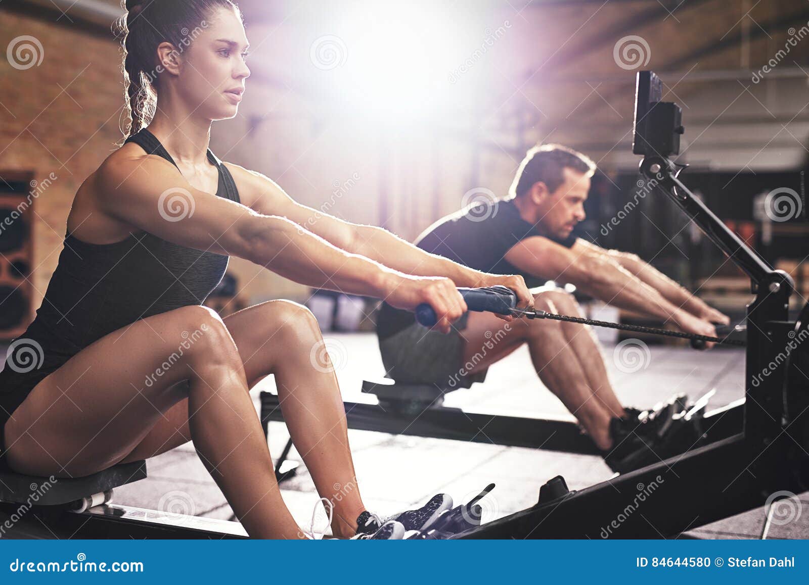 people having hard workout on rowing machines