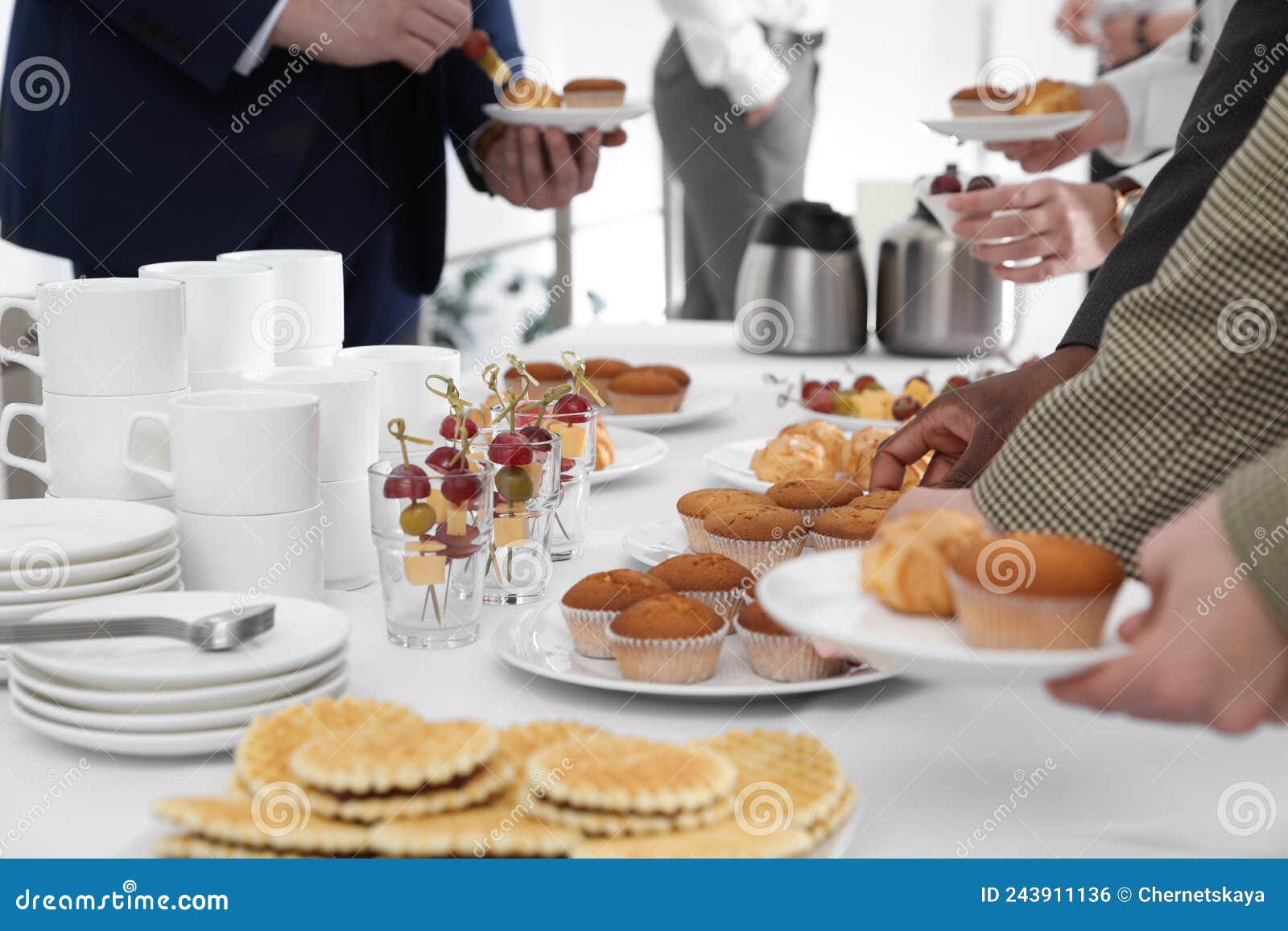 People Near Table with Different Delicious Snacks during Coffee Break