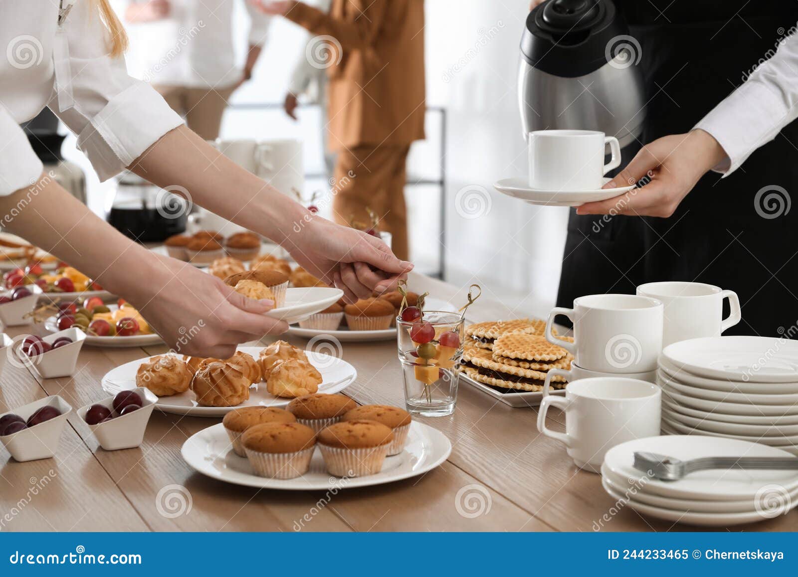People Near Table with Dishware and Different Delicious Snacks during