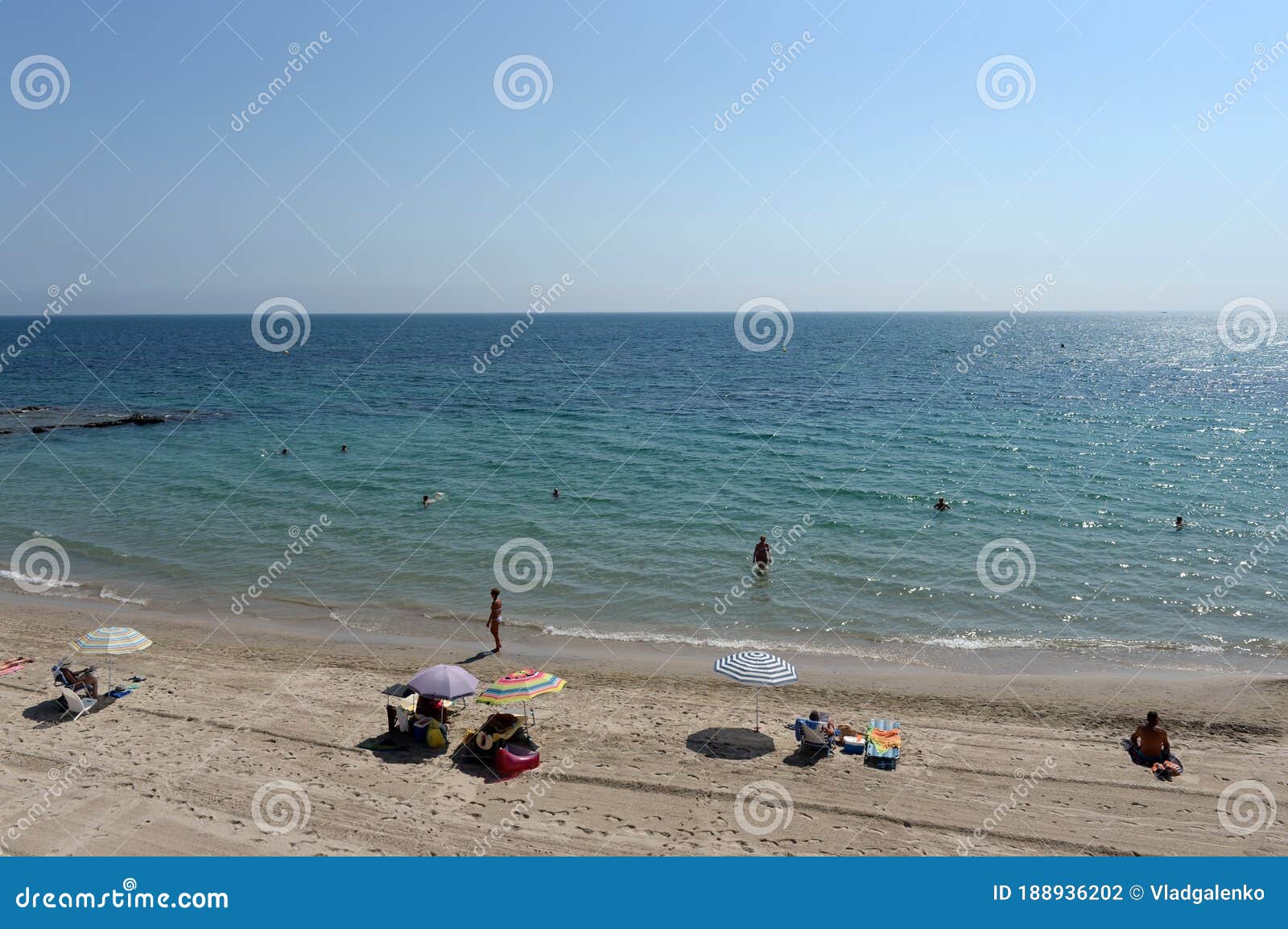 people relax on the sandy beach of playa de aguamarina, province of alicante, spain