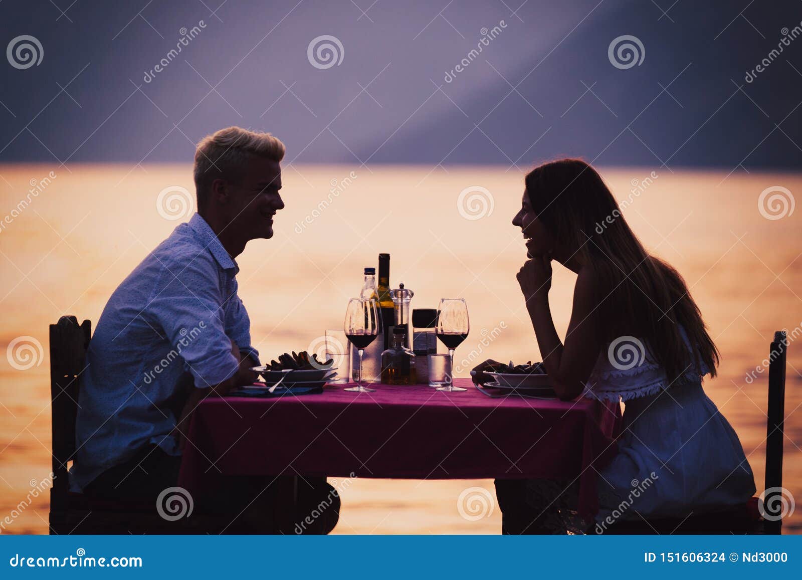 people, vacation, love and romance concept. young couple enjoying a romantic dinner on beach.