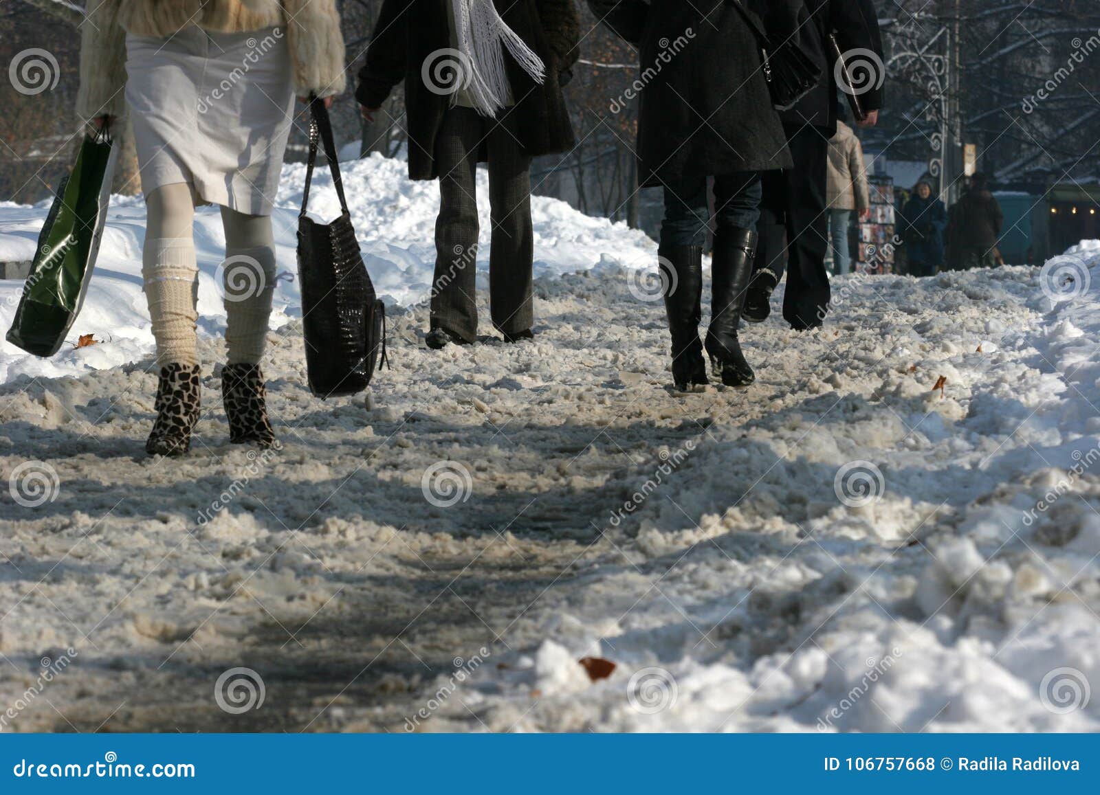 People Walk on a Very Snowy Sidewalk. People Step on a a Icy Pathway