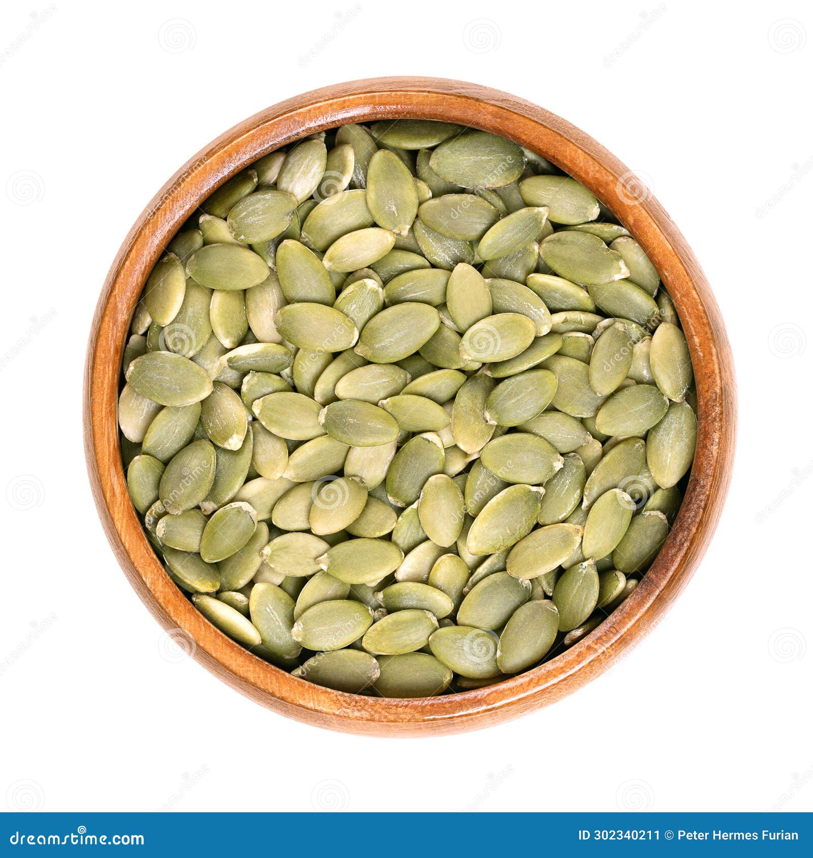 pepitas, hulled pumpkin seeds after shelling, in a wooden bowl