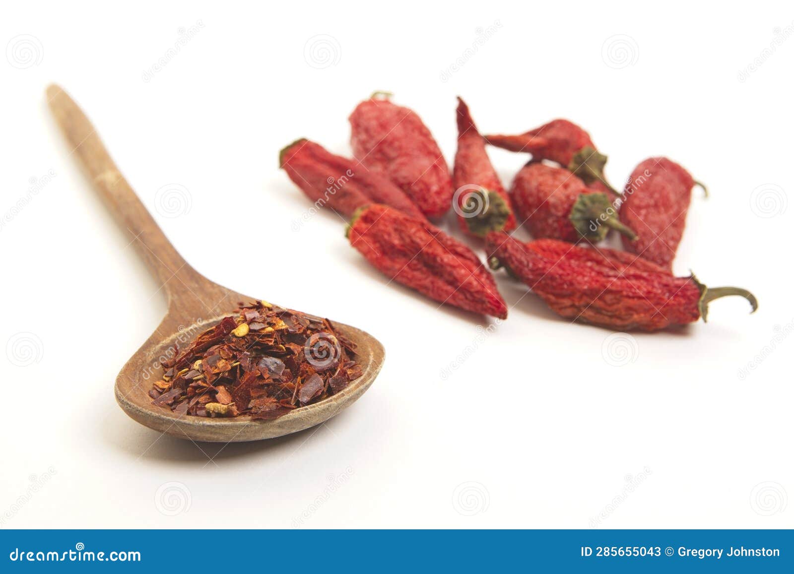 pepper flakes on a spoon and whole peppers