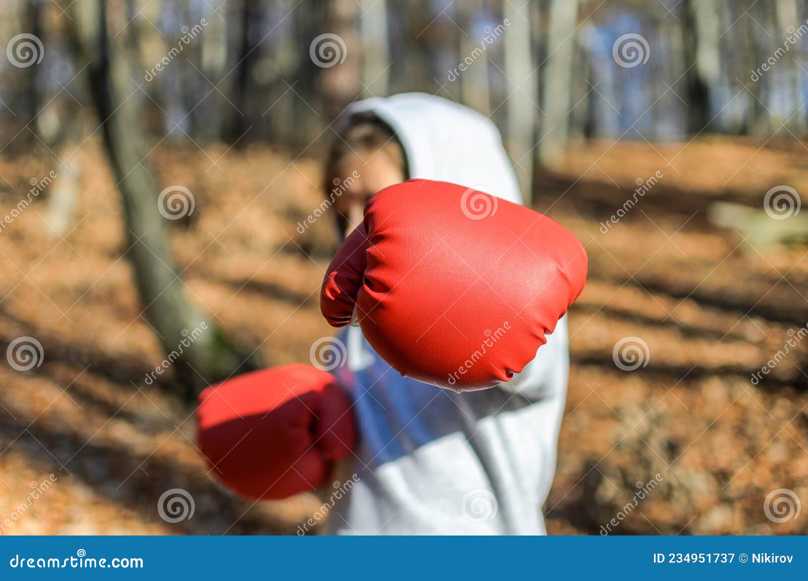 Pequeña Adorable Niña En Un Traje De Chándal Con Una Capucha En La Cabeza  Con Guantes De Boxeo Rojo Boxeando En La Calle En El Fre Foto de archivo -  Imagen de