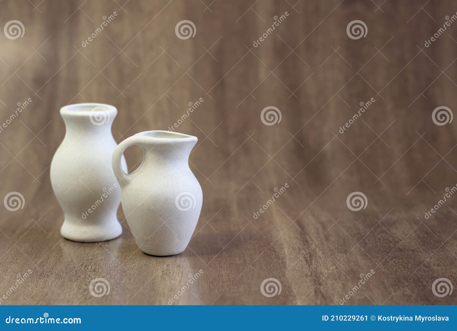 Dos jarrones de cerámica sobre una mesa de madera fondo oscuro cerrar