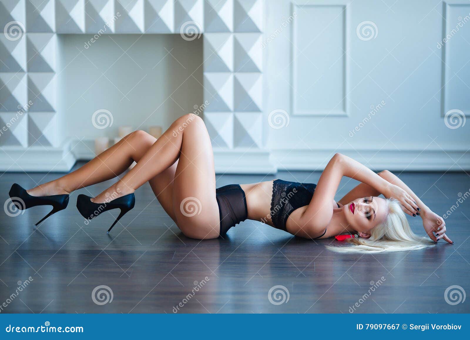 Happy pretty blonde woman model in red bodysuit stands looking at her  perfect legs hips buttocks over white background Stock Photo by ©dml5050  446843832