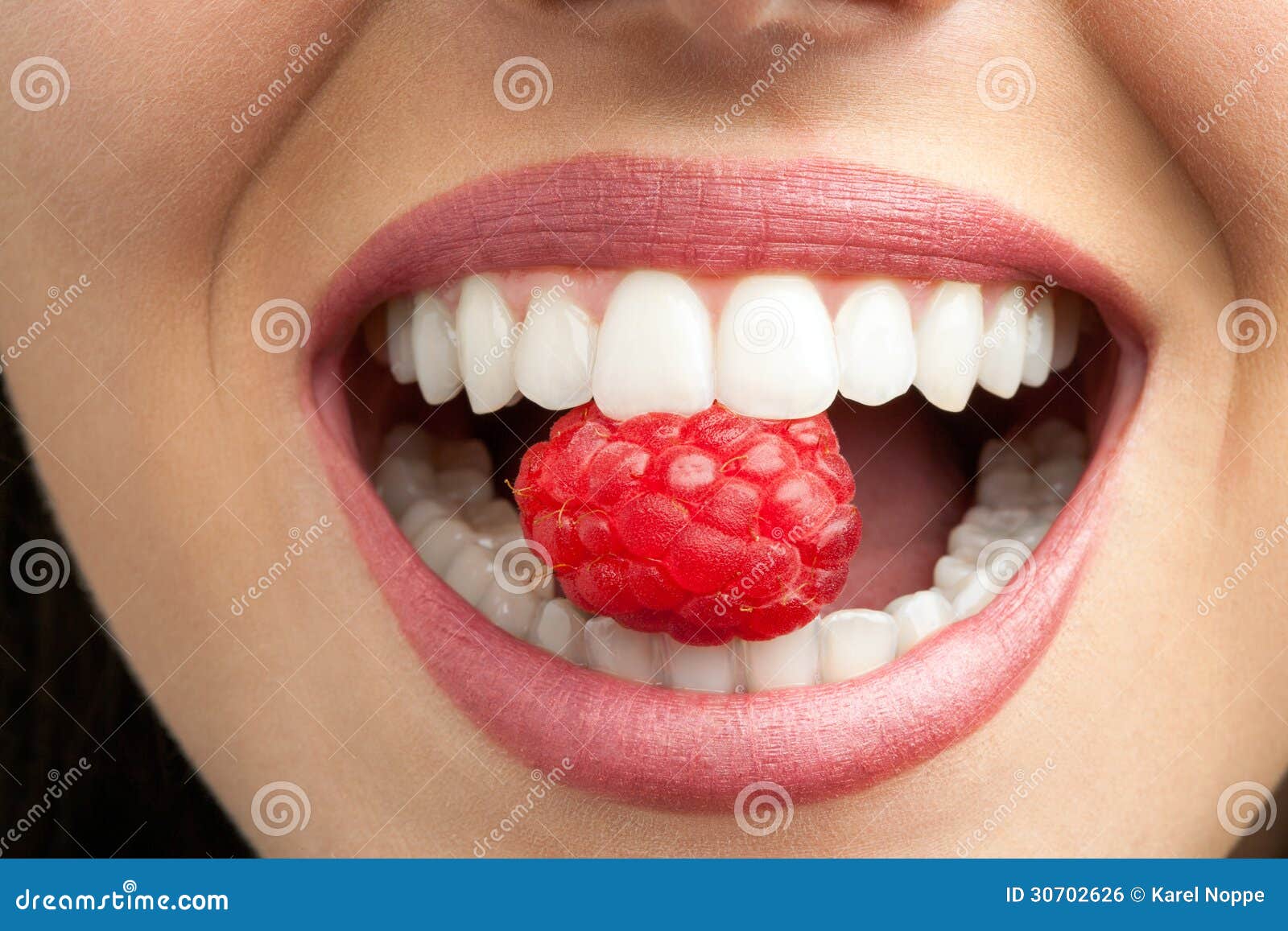 perfect teeth biting raspberry.