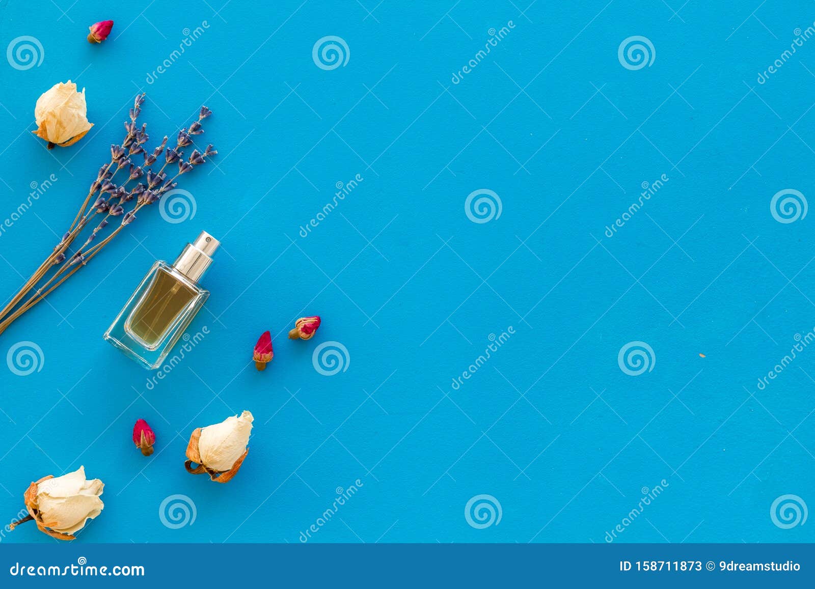 Perfume and Flowers Composition on Blue Background Top View Pattern