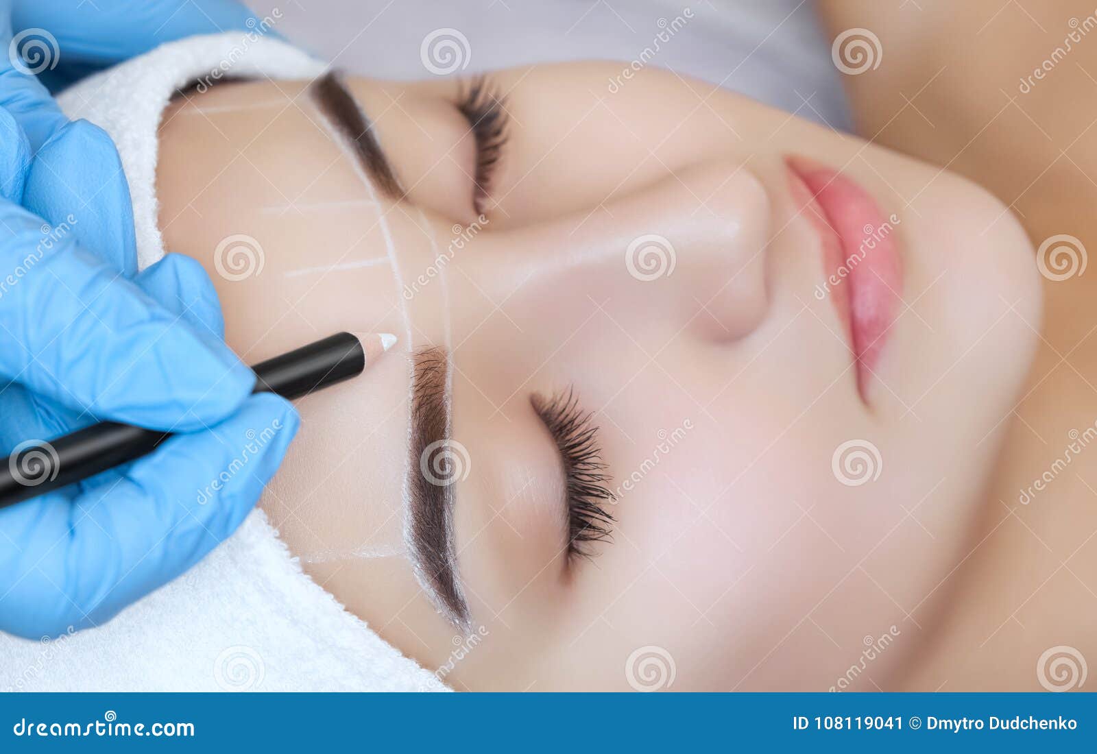 permanent make-up for eyebrows of beautiful woman with thick brows in beauty salon.