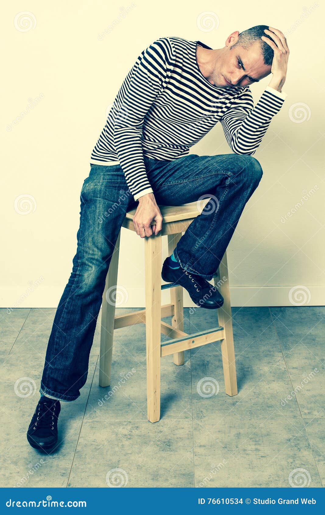 Perplexed Man Sitting on Stool, Holding His Head for Problems Stock