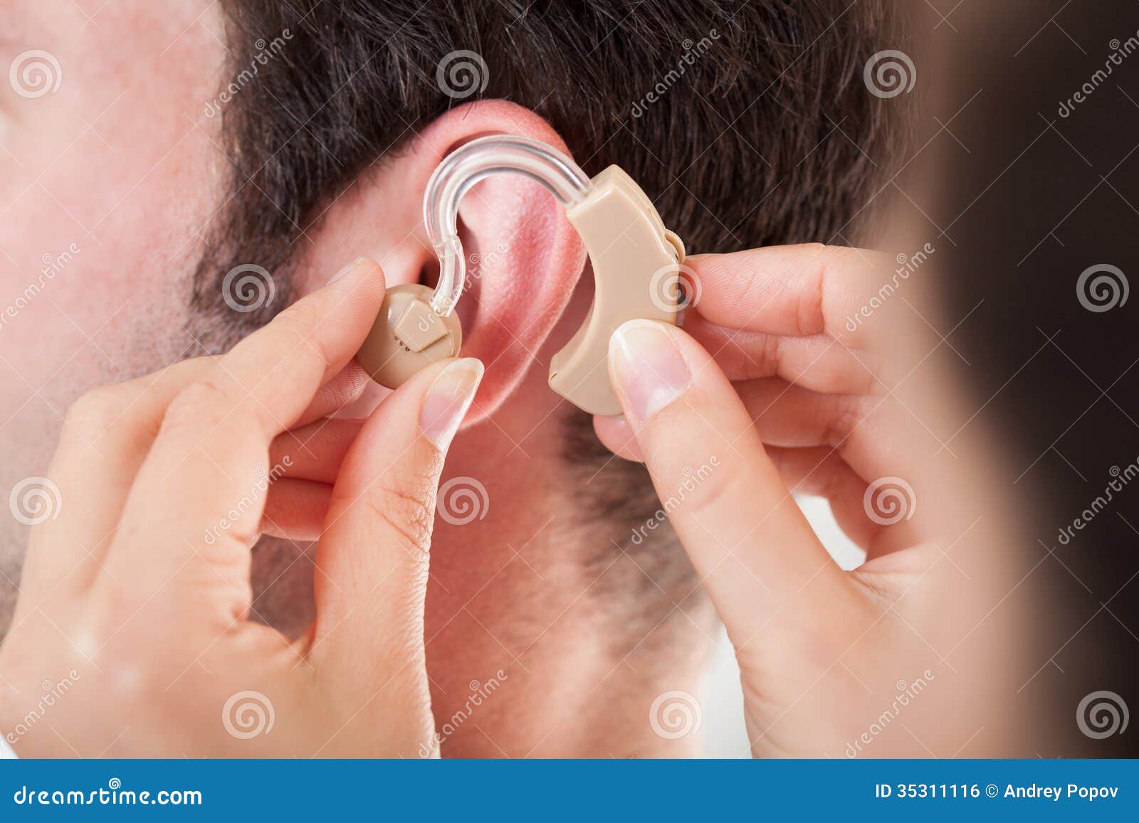 person adjusting hearing aid