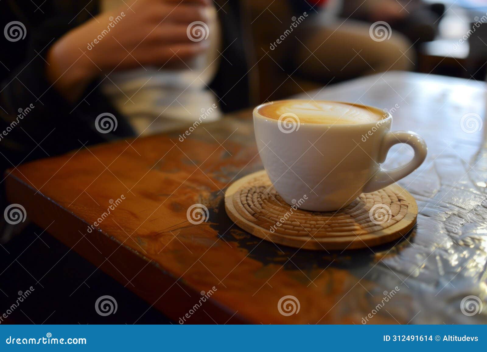 person at a caf, a coaster with a cappuccino cup on top