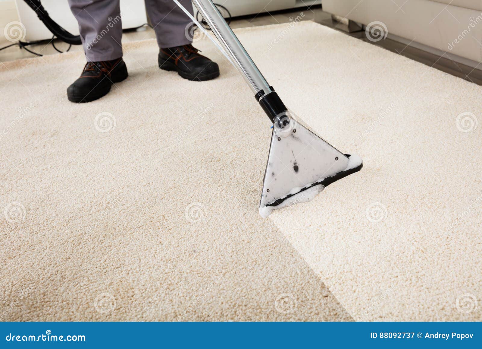 person cleaning carpet with vacuum cleaner