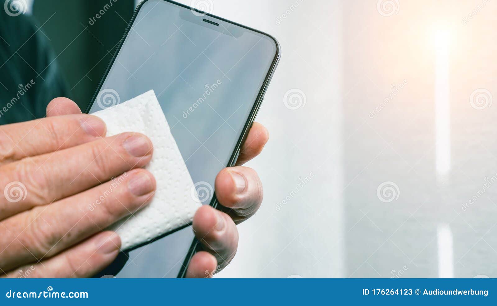 Person Cleaning Mobile Phone Screen with Disinfecting Wipes for