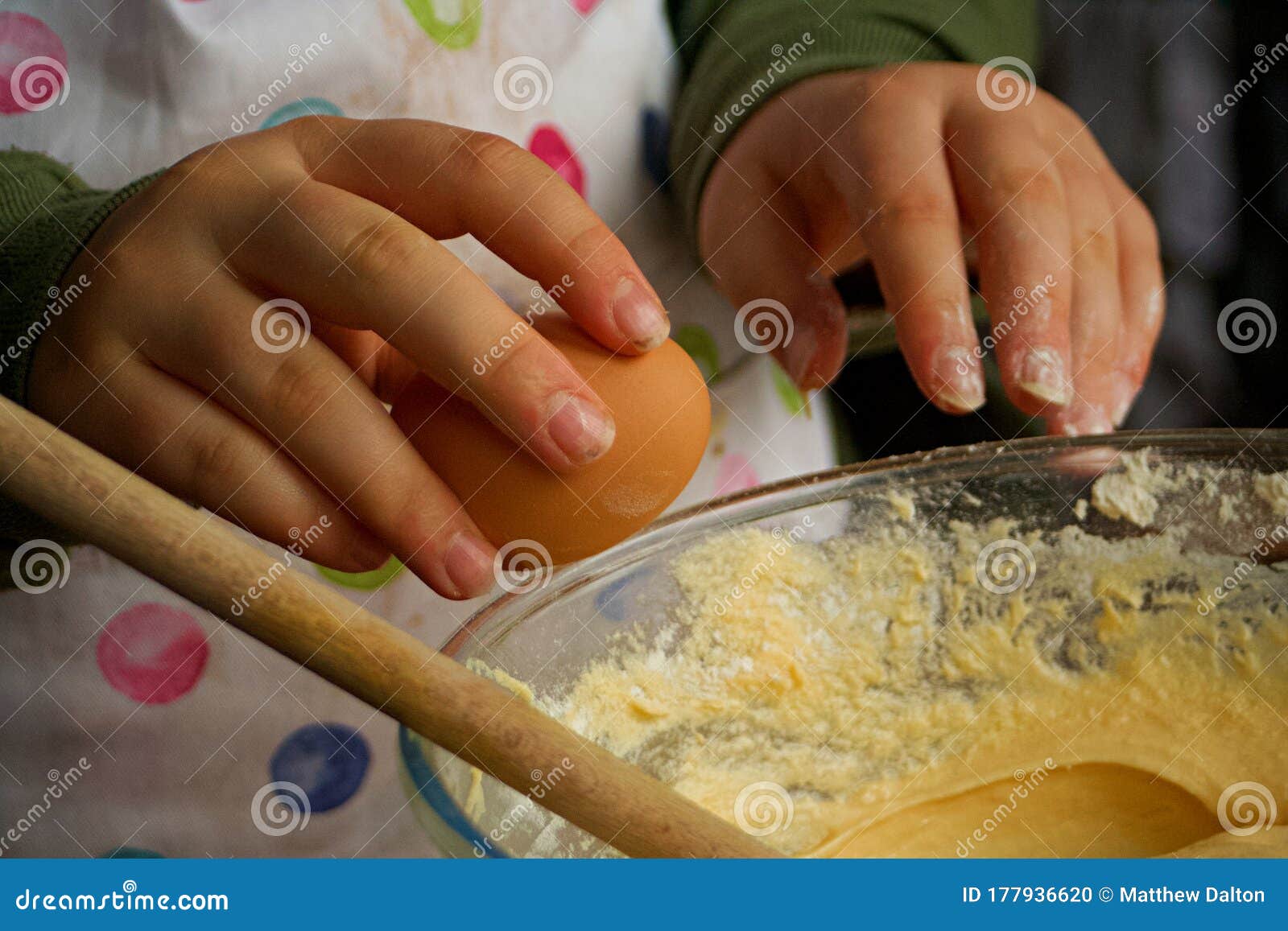 A Person Cracking an Egg into a Bowl of Cake Mixture. Stock Photo
