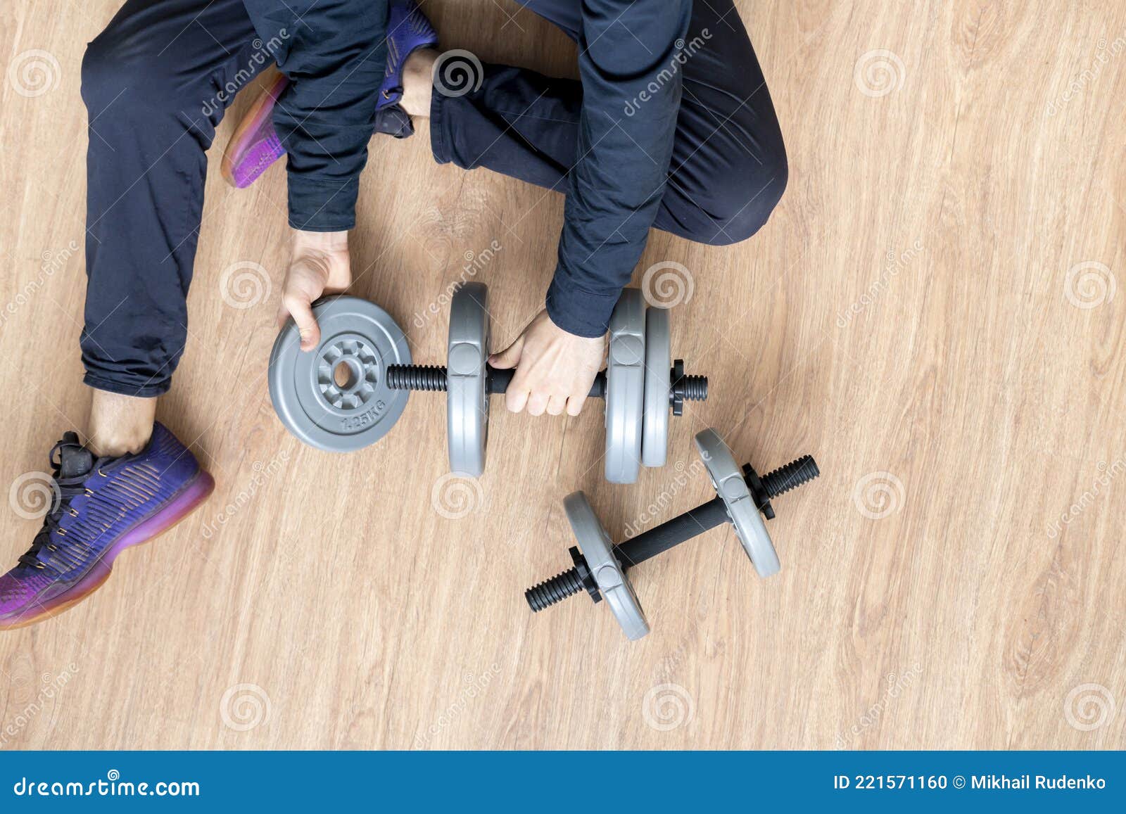 a person doing workout and put on a weght disc on a barbell dumbbell