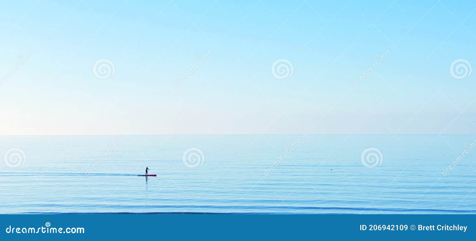 peace tranquility serene serenity sup paddle boarding on a calm clear blue water ocean sea horizon copyspace