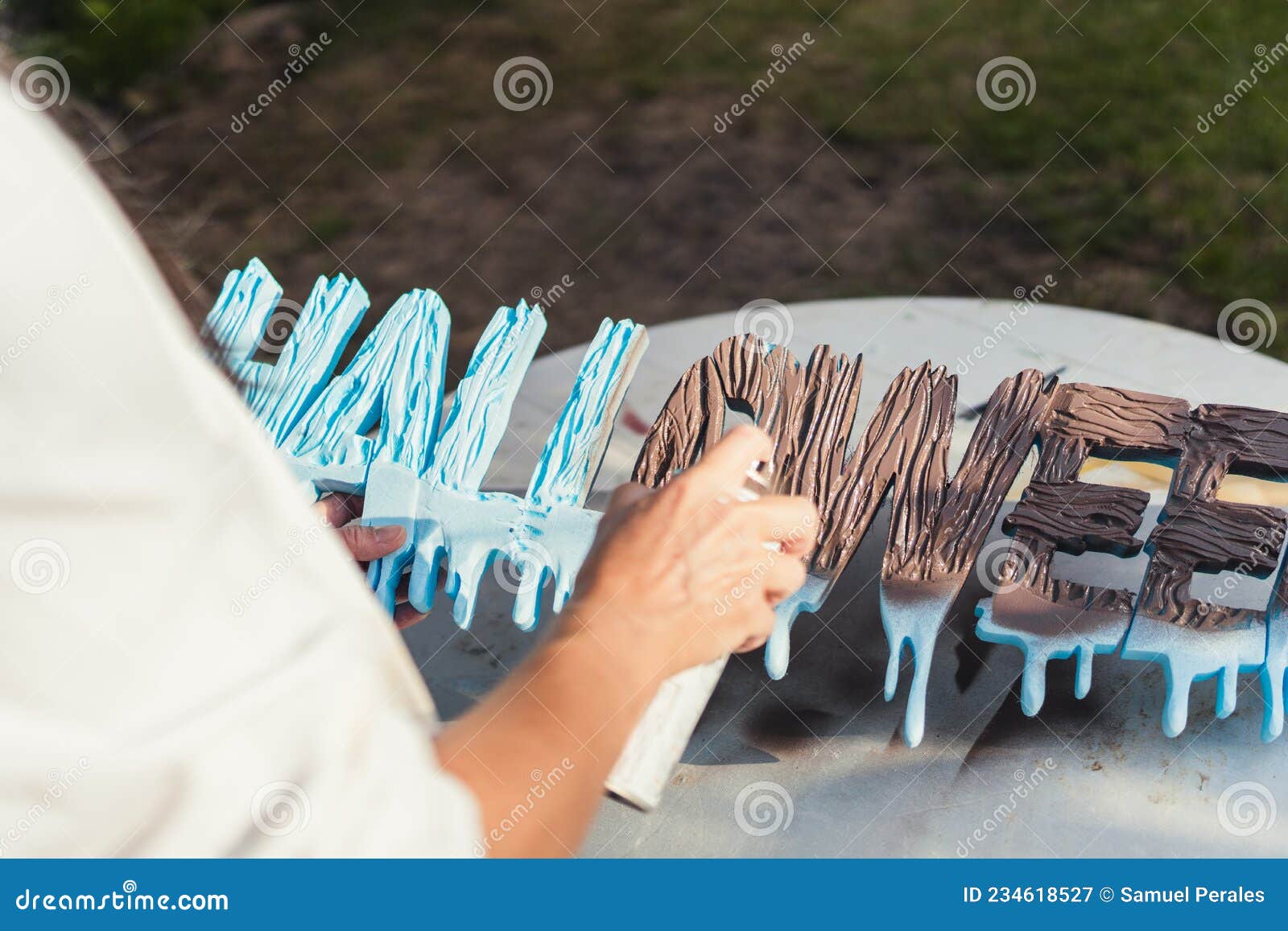 person painting polystyrene letters with brown paint in spray