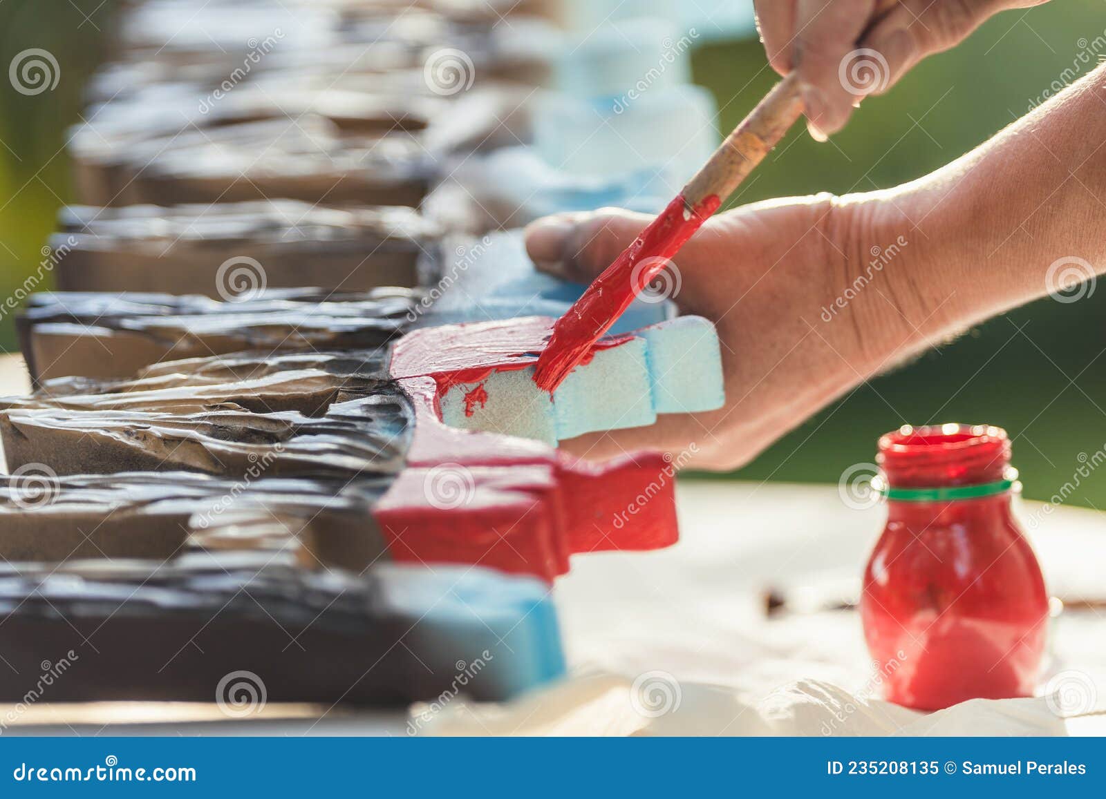 person painting polystyrene letters in red outside