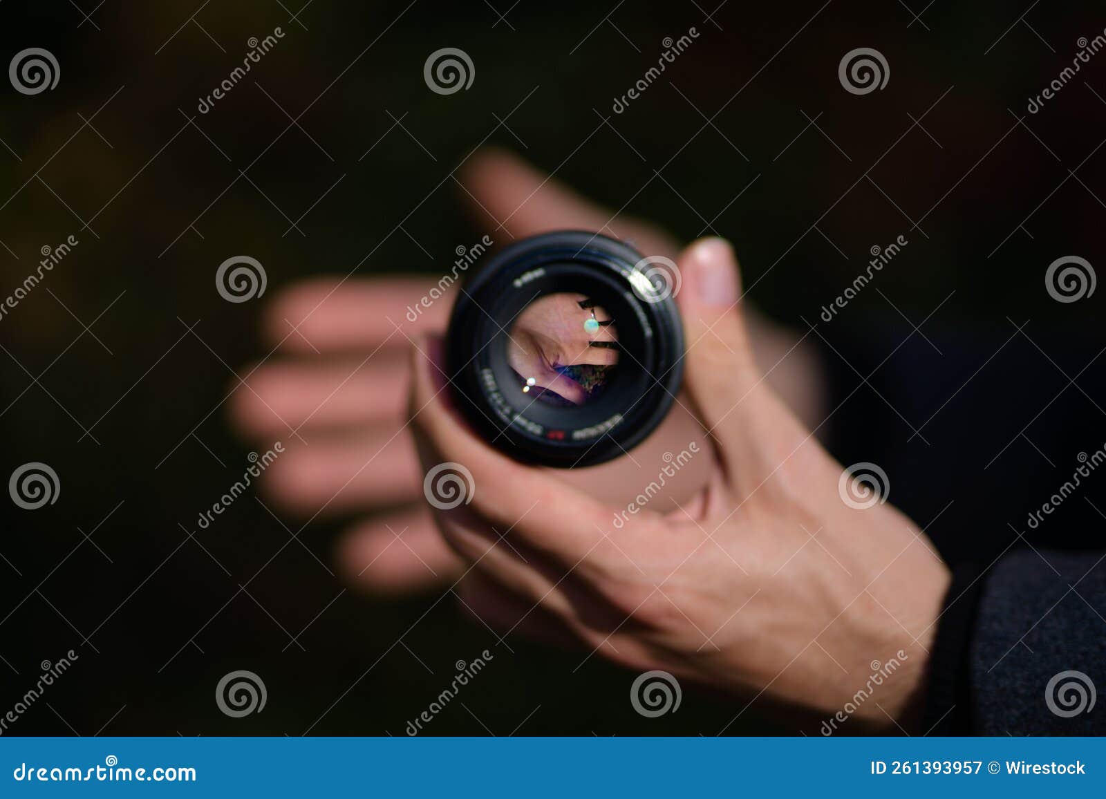 person's hand holding a 50 mm minolta camera lens with focus on the inside of the lens