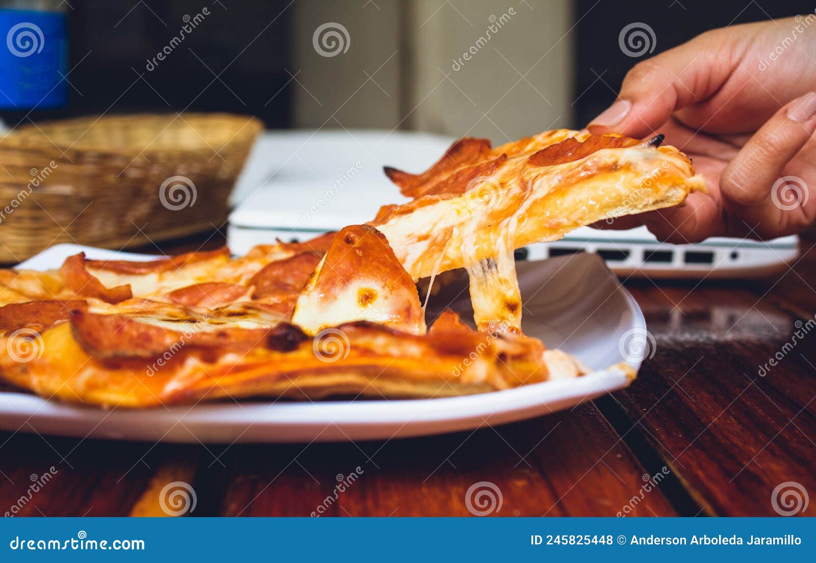 person's hand holding piece of pizza in restaurant