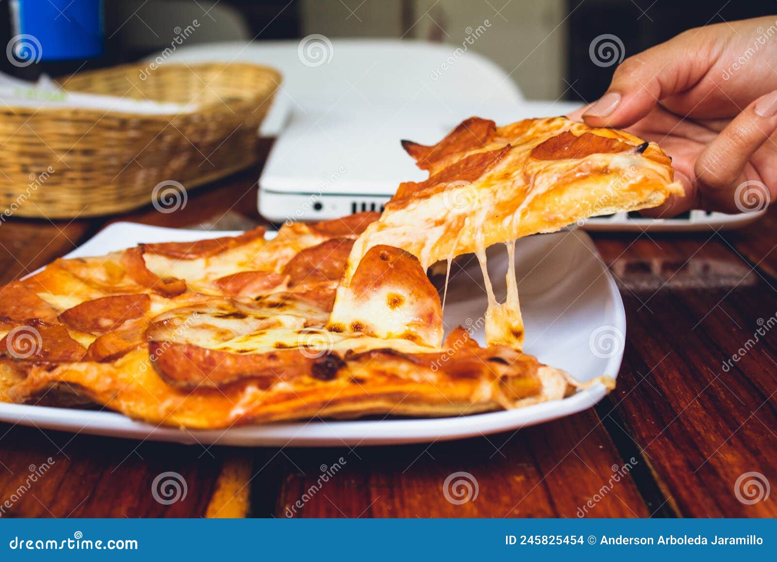 person's hand holding piece of pizza in restaurant