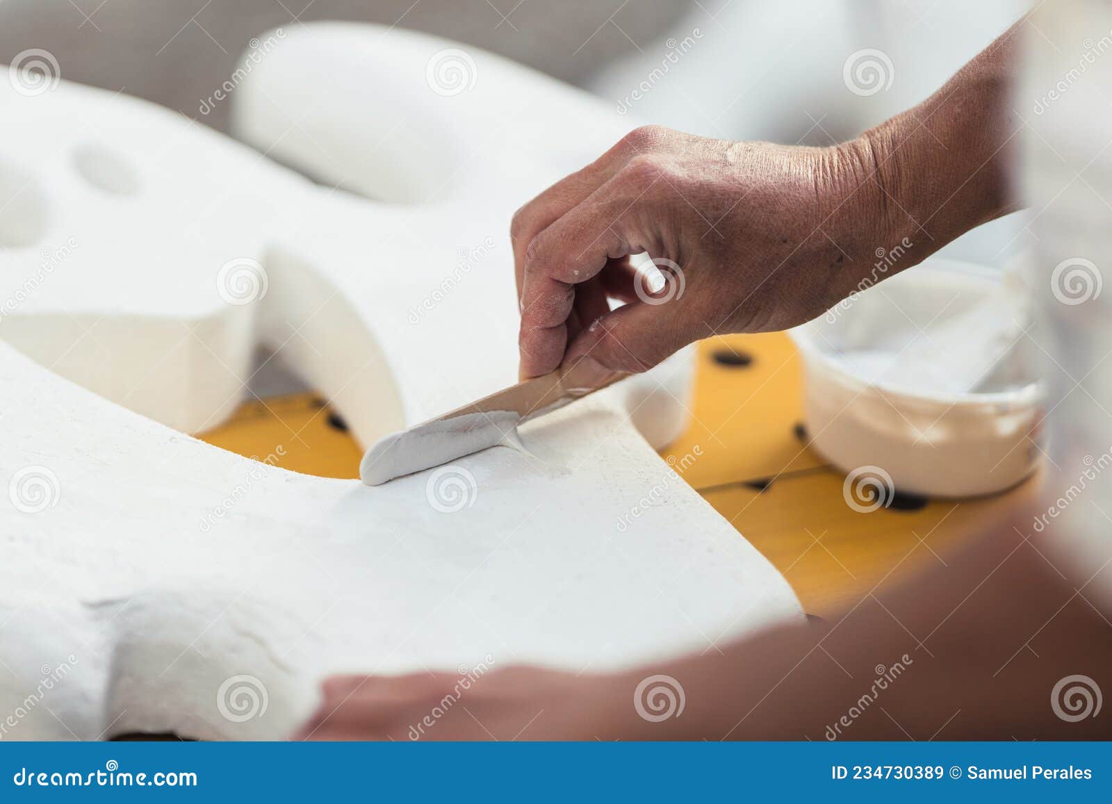 person smoothing with cream the surface of a polystyrene figure with a spatula