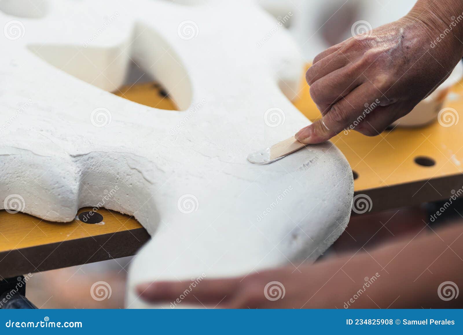 person spreading cream to smooth a polystyrene figure using a spatula