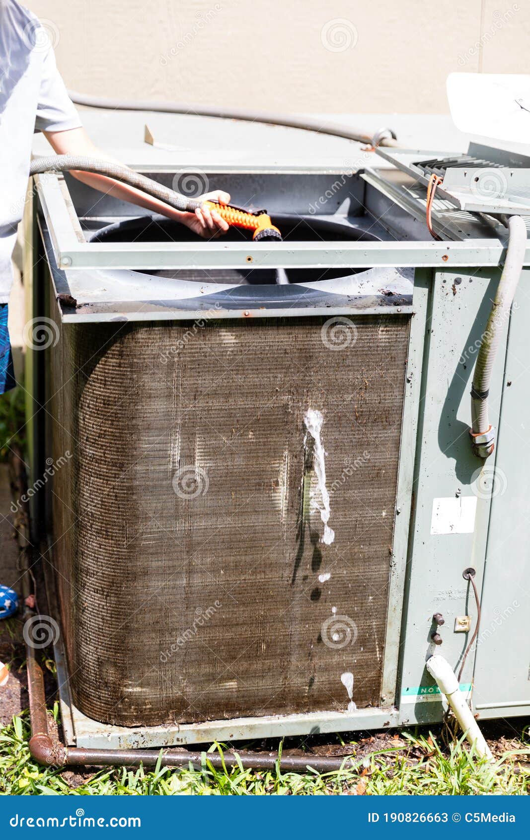 Person Using Water Hose To Clean Condenser Coil on Air Conditioner